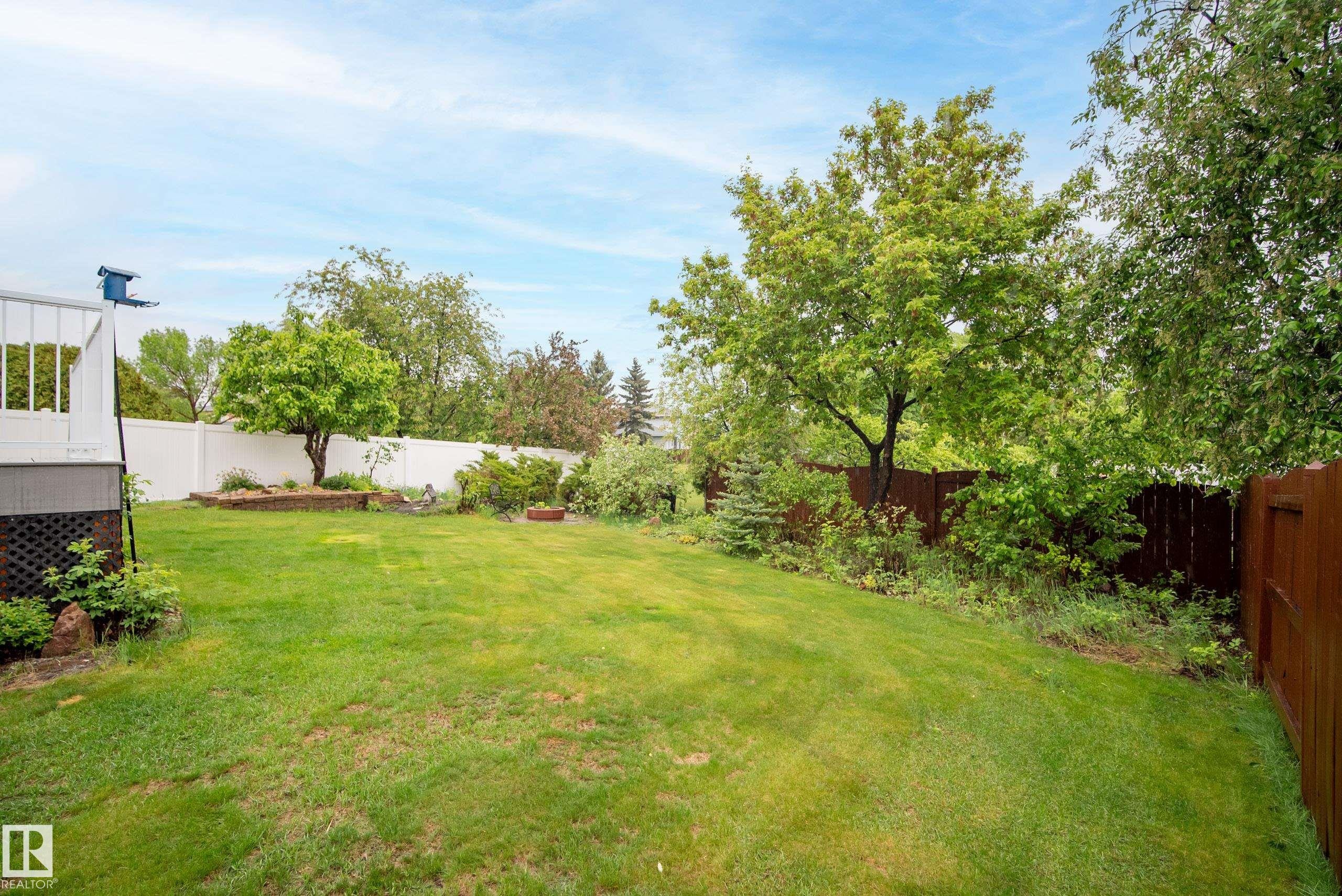 Expansive backyard featuring a large grass lawn, mature trees, and a privacy fence - 15503 62 Street, Edmonton, AB