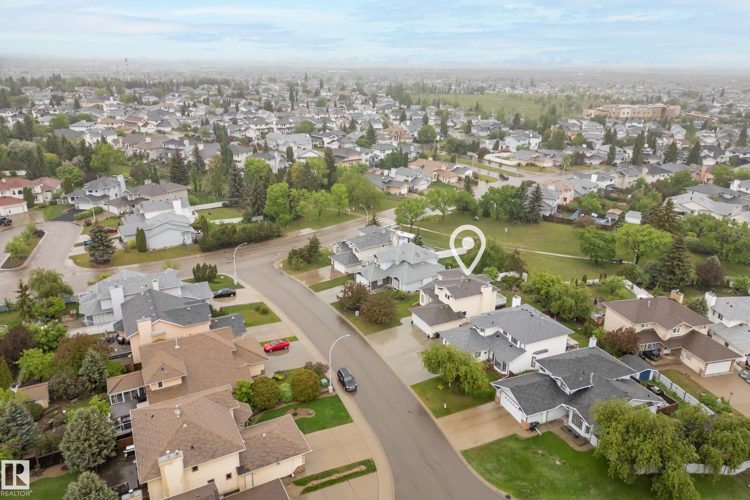 Aerial perspective showcasing a residential area with varied housing styles, mature trees, and paved streets - 15503 62 Street, Edmonton, AB