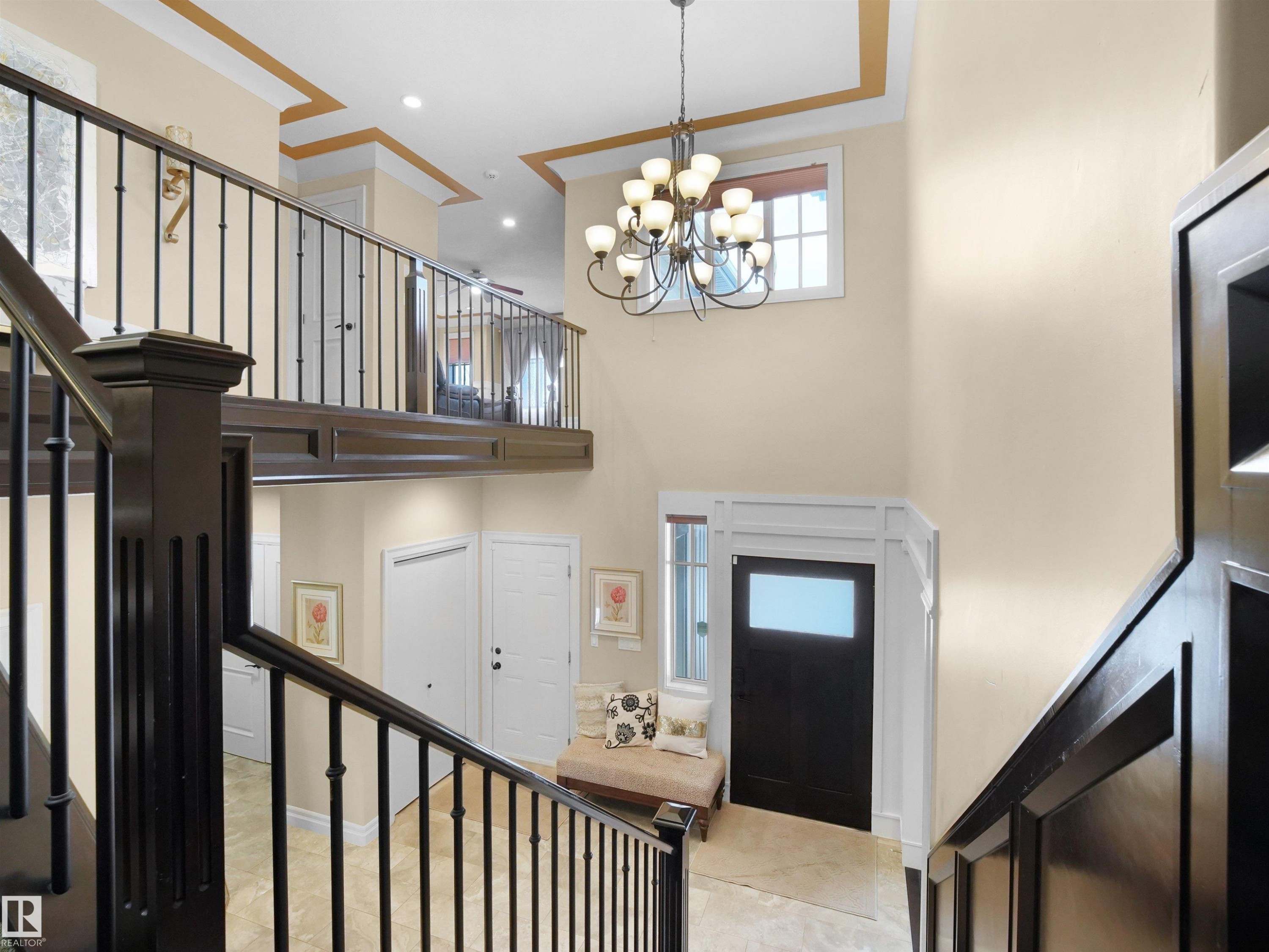 Two-story foyer featuring a grand staircase with dark wood-finish newel posts and wrought iron balusters - 2019 Cameron Ravine Way Nw, Edmonton, AB
