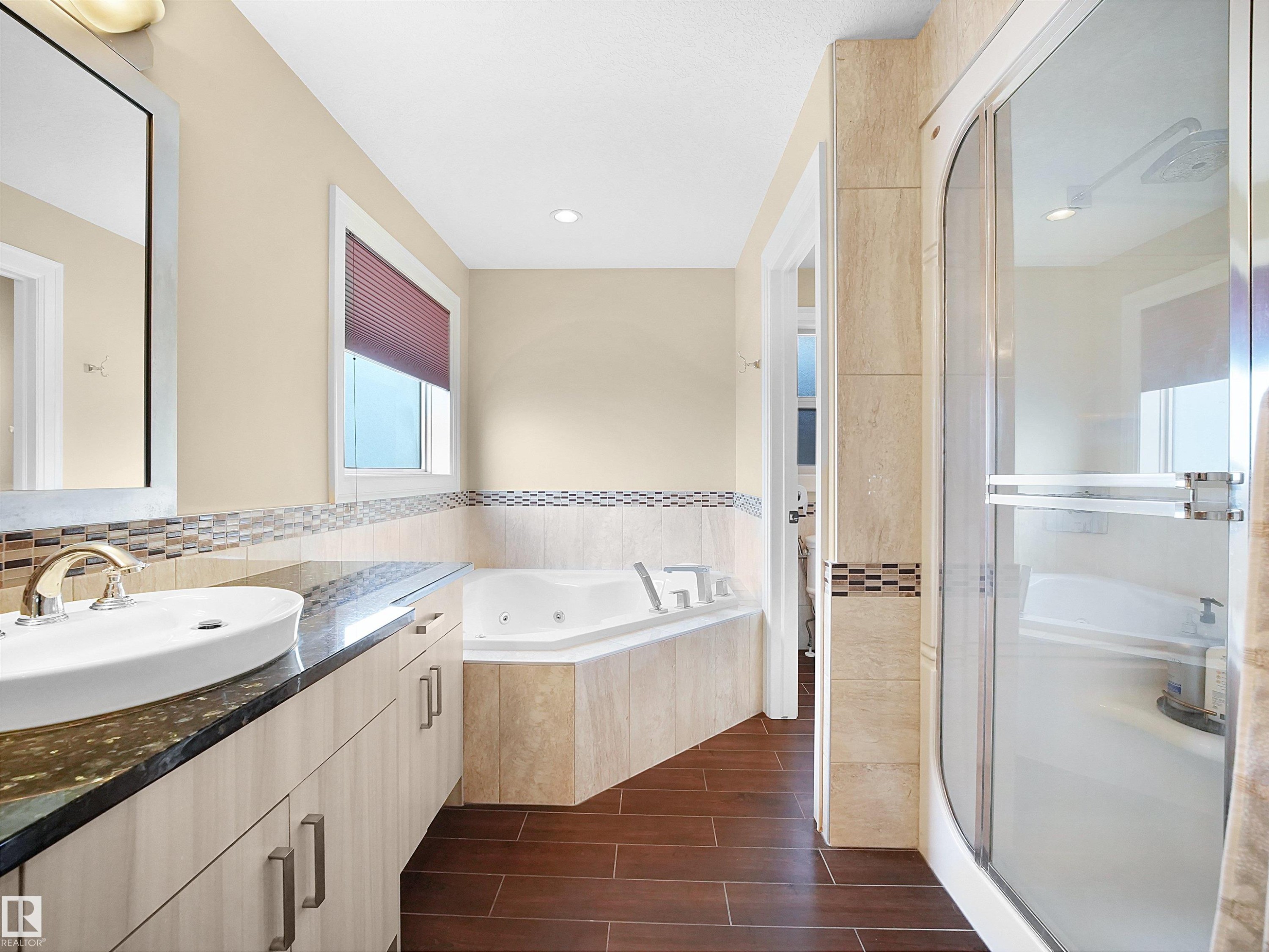 Bathroom featuring wood-finish flooring and a corner soaking tub - 2019 Cameron Ravine Way Nw, Edmonton, AB