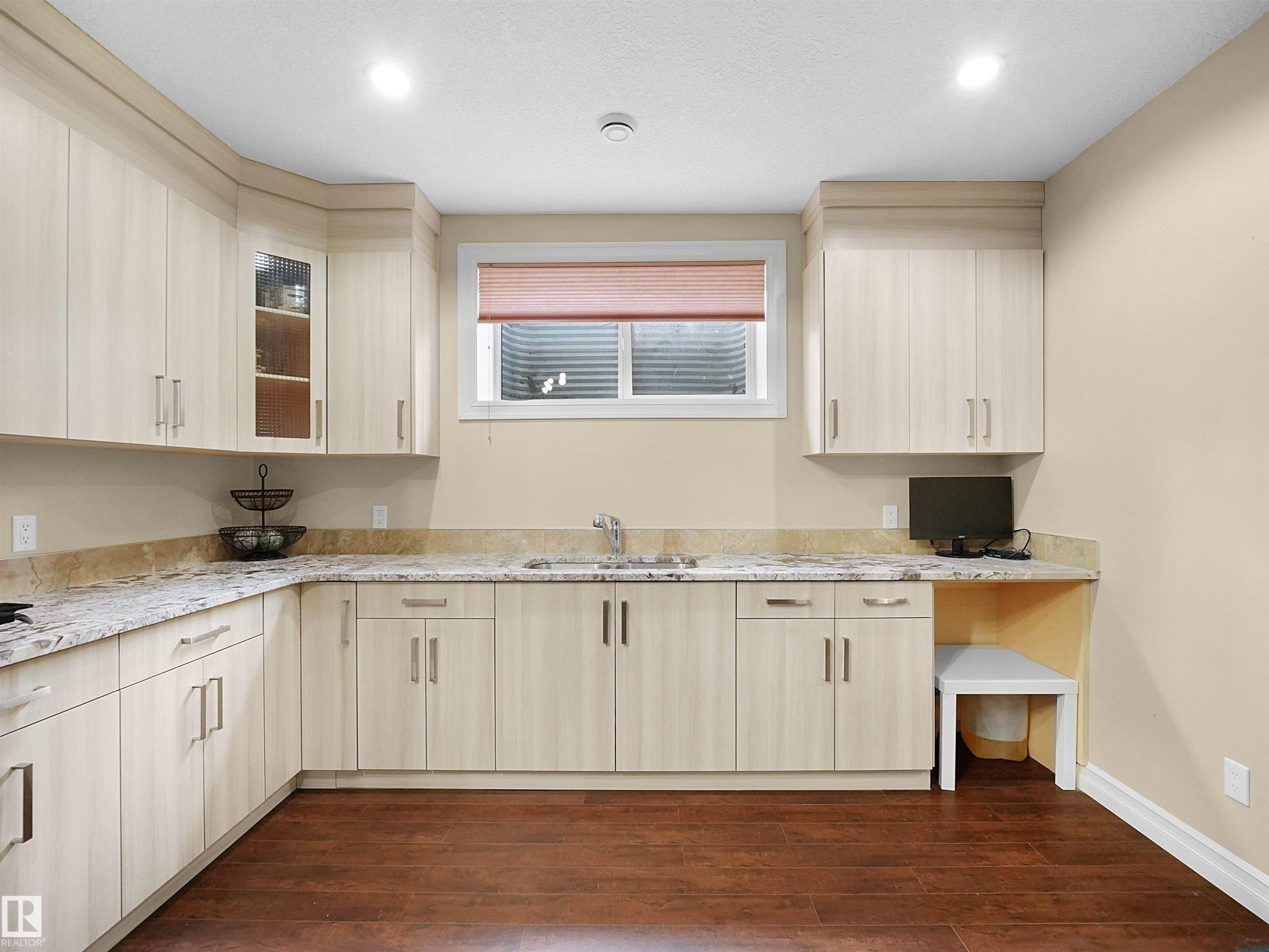 Kitchenette featuring light wood-finish cabinetry, granite countertops, and a stainless steel sink with a single-handle faucet - 2019 Cameron Ravine Way Nw, Edmonton, AB