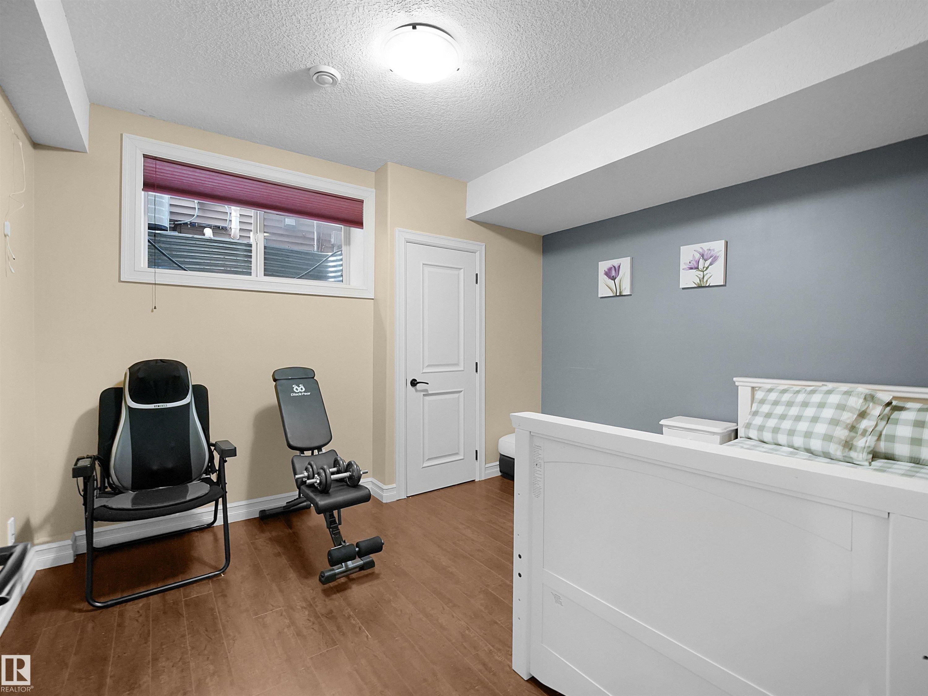 Spacious room featuring wood-finish flooring, a neutral color palette, and a window with a pleated shade - 2019 Cameron Ravine Way Nw, Edmonton, AB