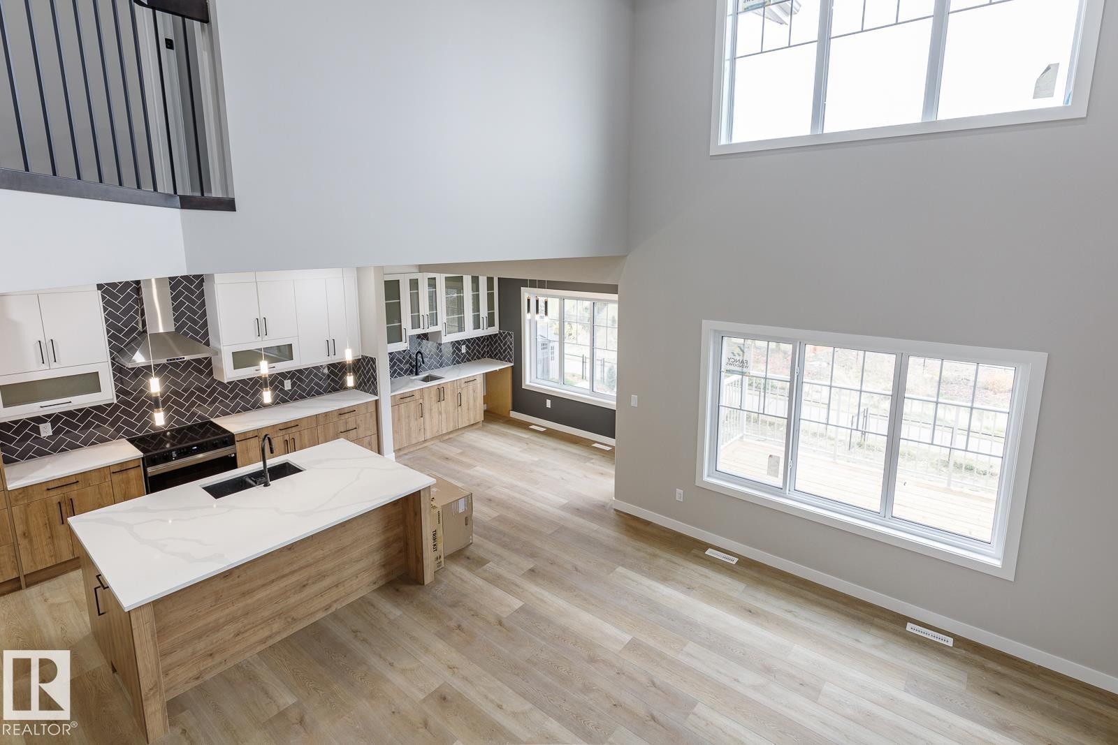 Open-concept living space featuring a two-story ceiling and wood-finish flooring - 50 Chartres Close, St. Albert, AB