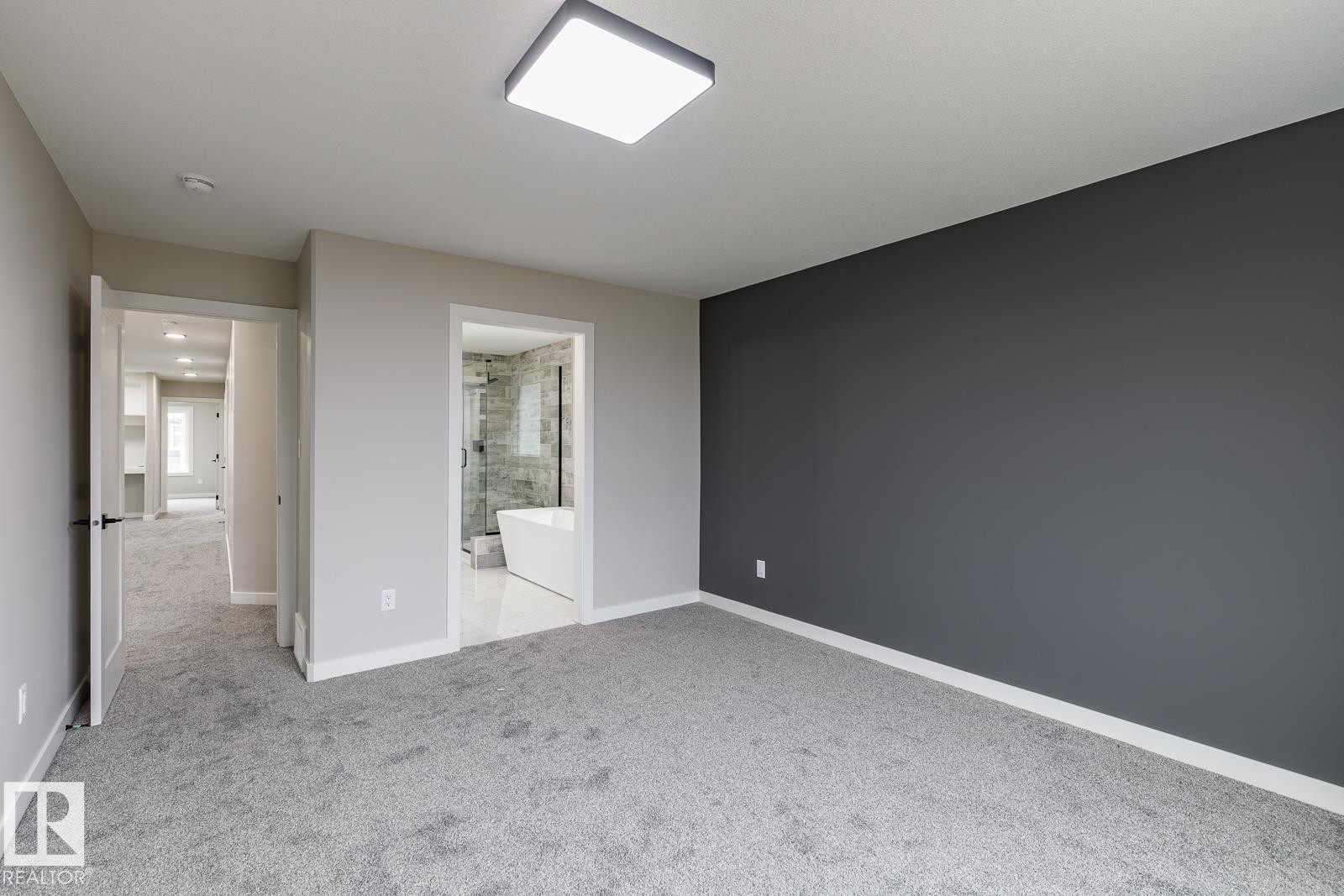 Spacious room featuring gray carpet flooring, a dark accent wall, and a contemporary flush-mount ceiling light - 50 Chartres Close, St. Albert, AB
