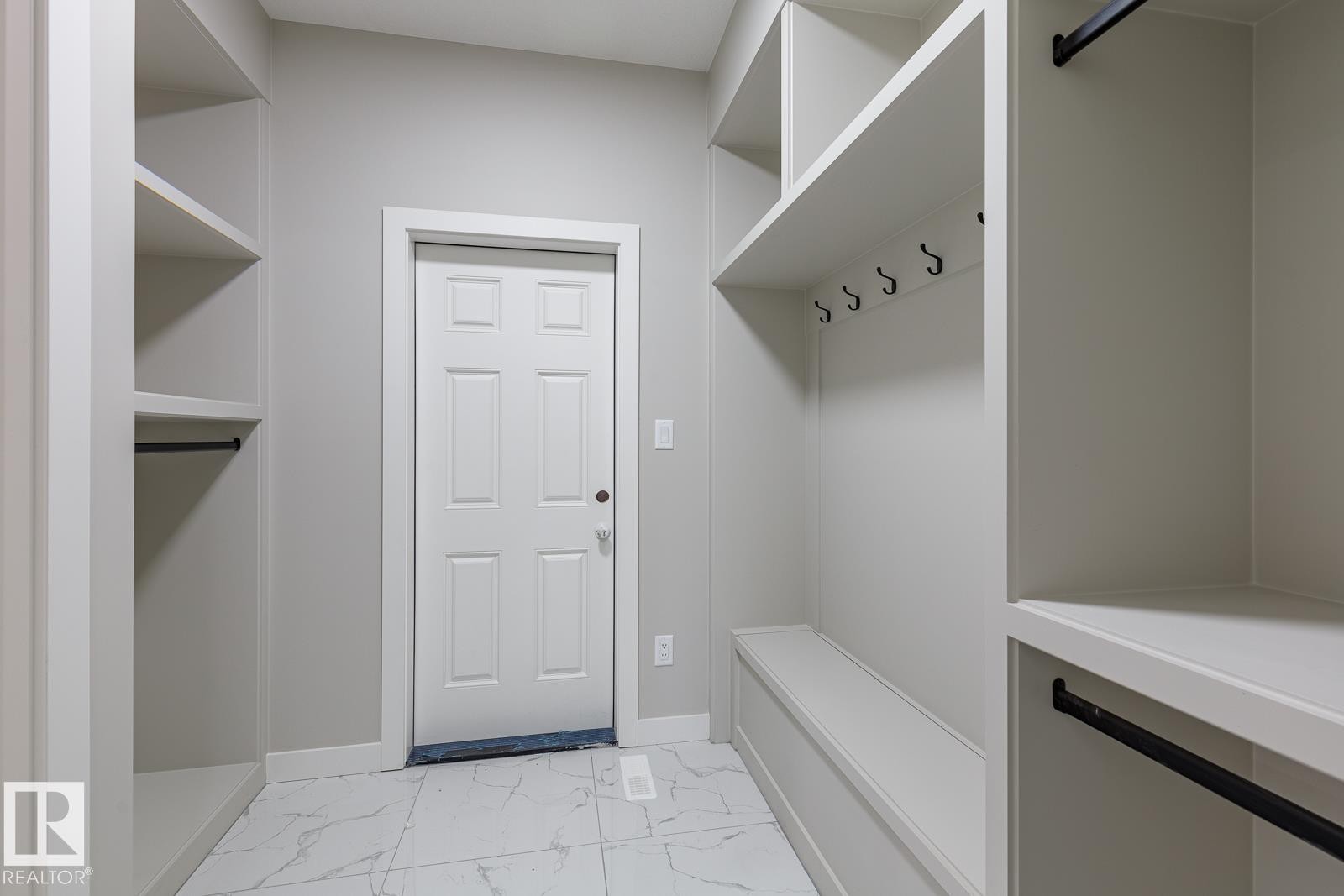 Entryway mudroom featuring built-in shelving, a storage bench, and white tile flooring - 50 Chartres Close, St. Albert, AB