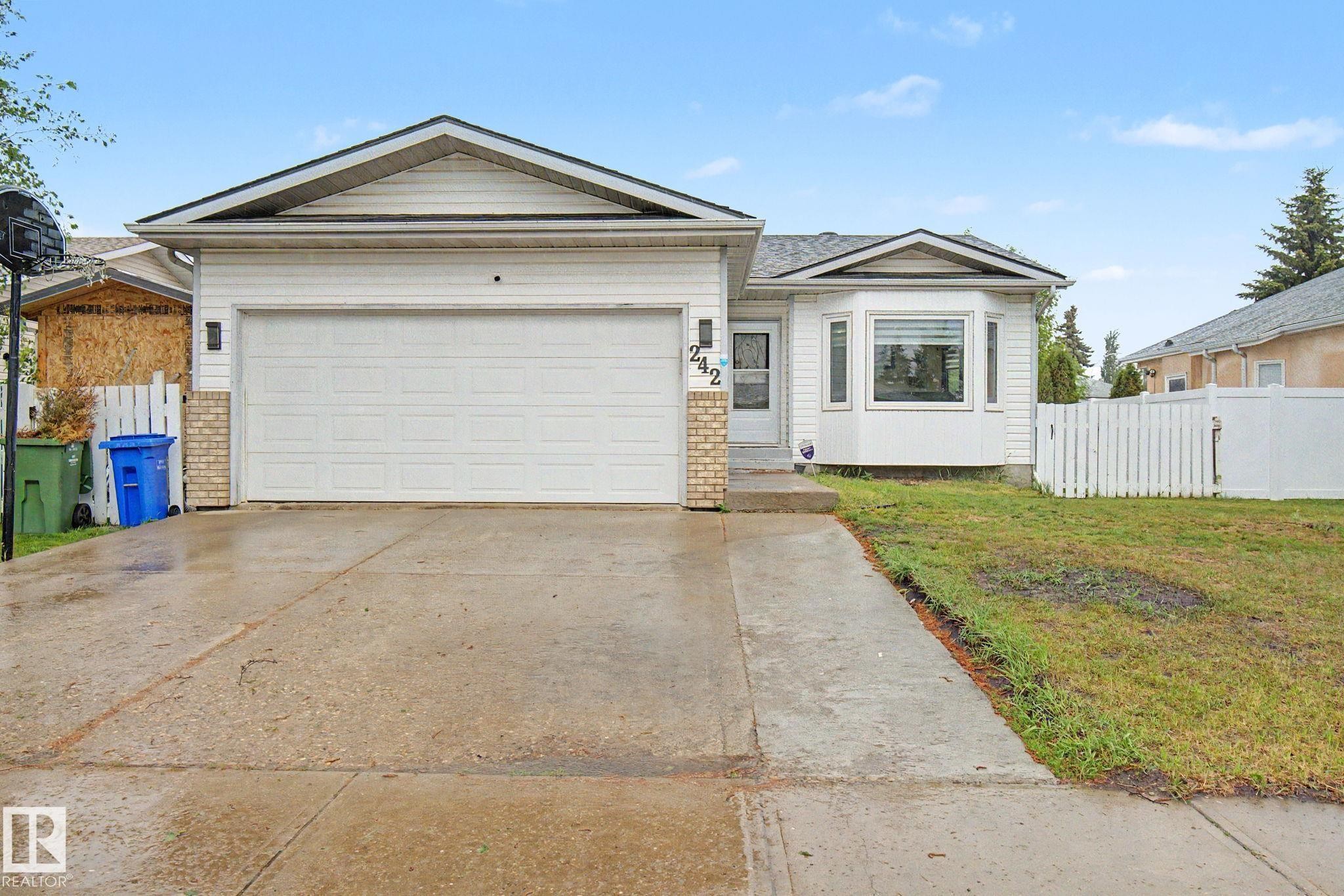 Single-story residence featuring white vinyl siding with brick accents, an attached garage, a bay window, and a concrete driveway - 242 Northmount Drive, Wetaskiwin, AB