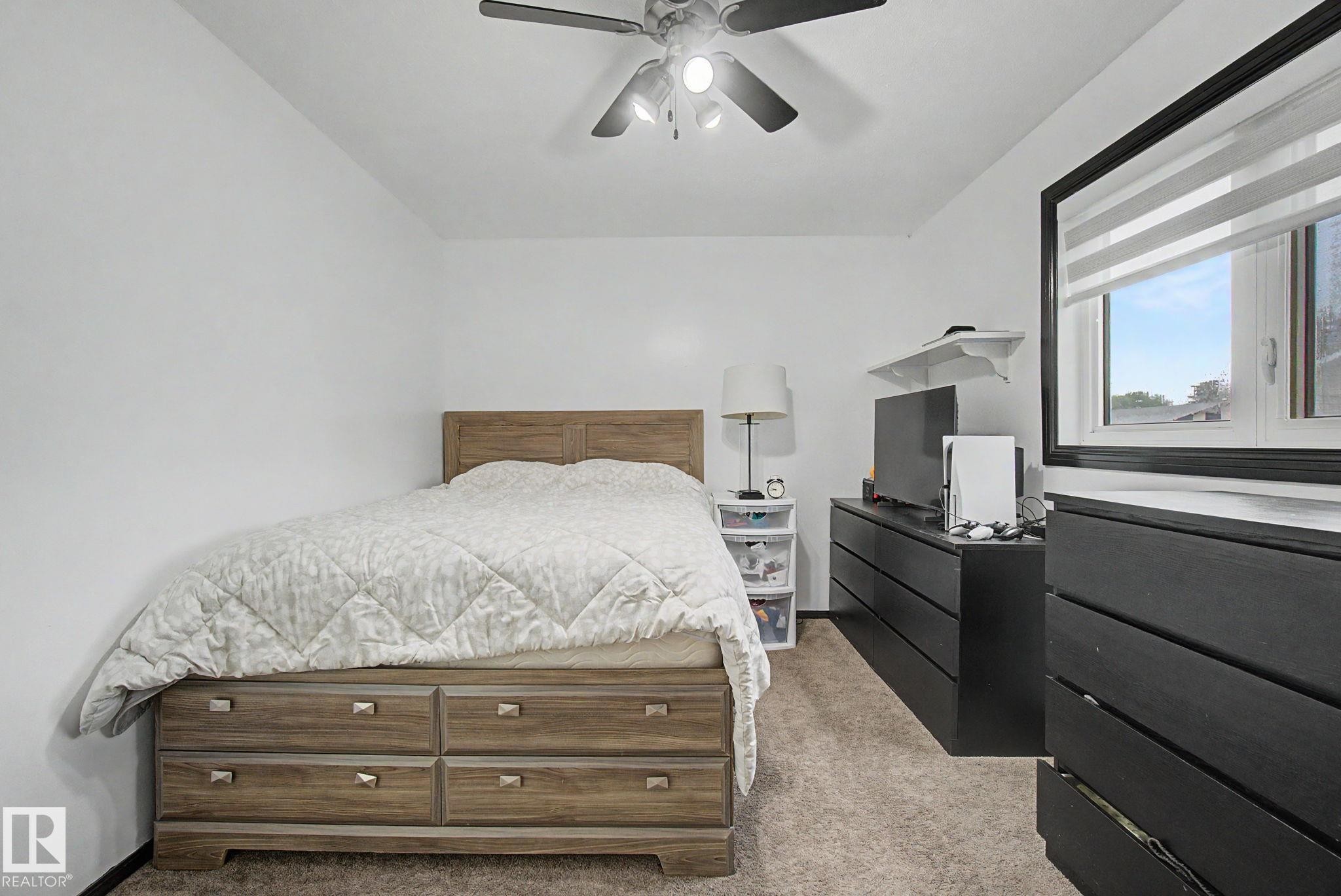 Room featuring neutral wall tones, light brown carpet, a ceiling fan with light fixture, and a window with horizontal blinds - 242 Northmount Drive, Wetaskiwin, AB