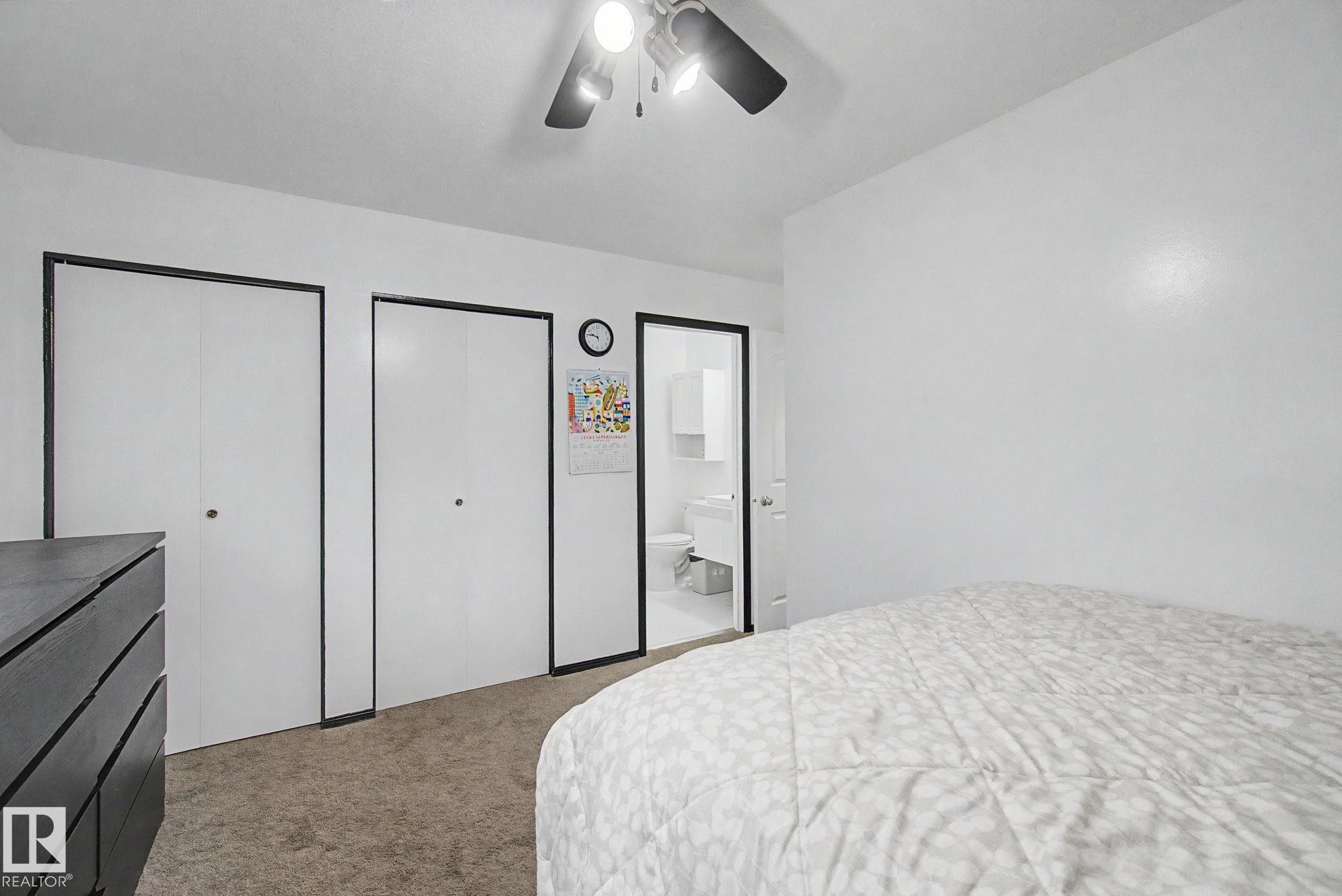 Bedroom featuring a ceiling fan, plush carpet, two bi-fold closet doors, and an entry to an additional space - 242 Northmount Drive, Wetaskiwin, AB