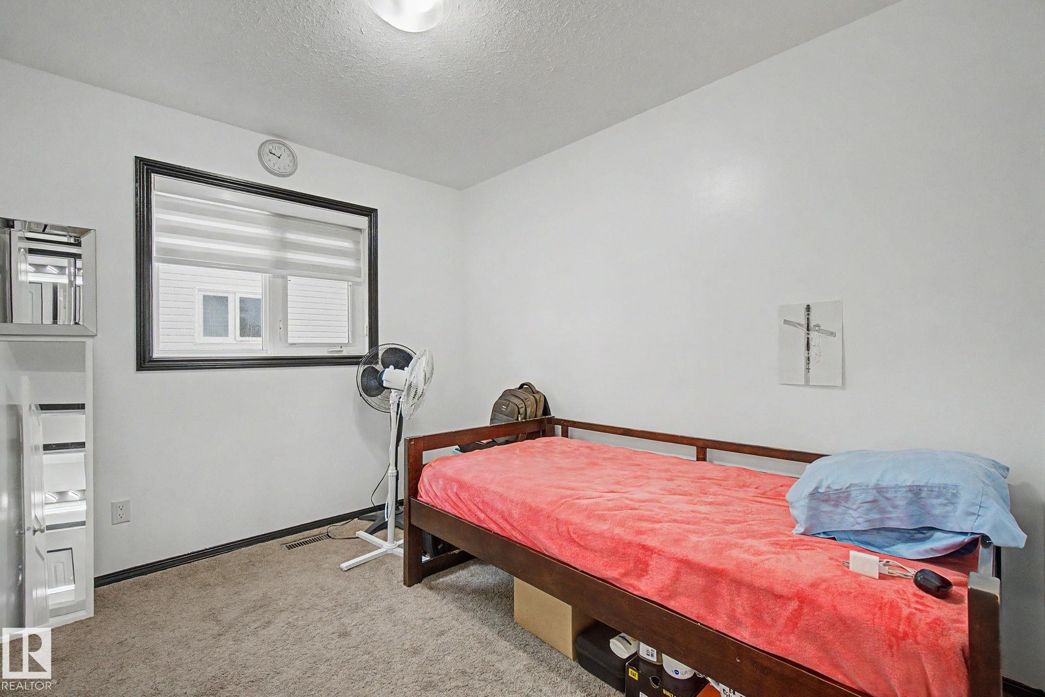 Bright interior room featuring a window with blinds, carpeted flooring, and white walls - 242 Northmount Drive, Wetaskiwin, AB