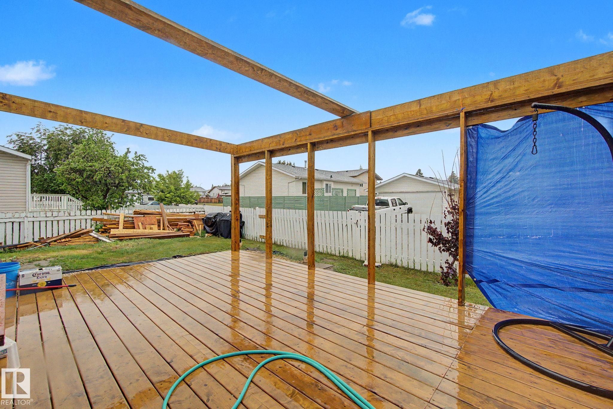 Spacious wood deck with a partial pergola structure, providing an outdoor extension to the property - 242 Northmount Drive, Wetaskiwin, AB