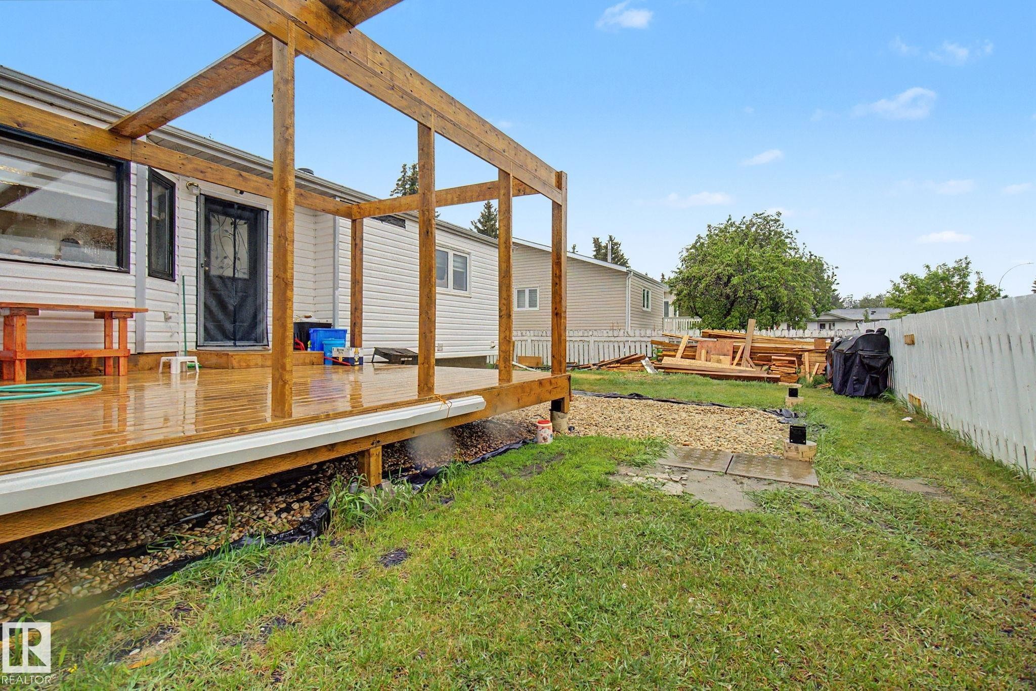 Outdoor wood-plank deck featuring a partial wooden pergola frame - 242 Northmount Drive, Wetaskiwin, AB