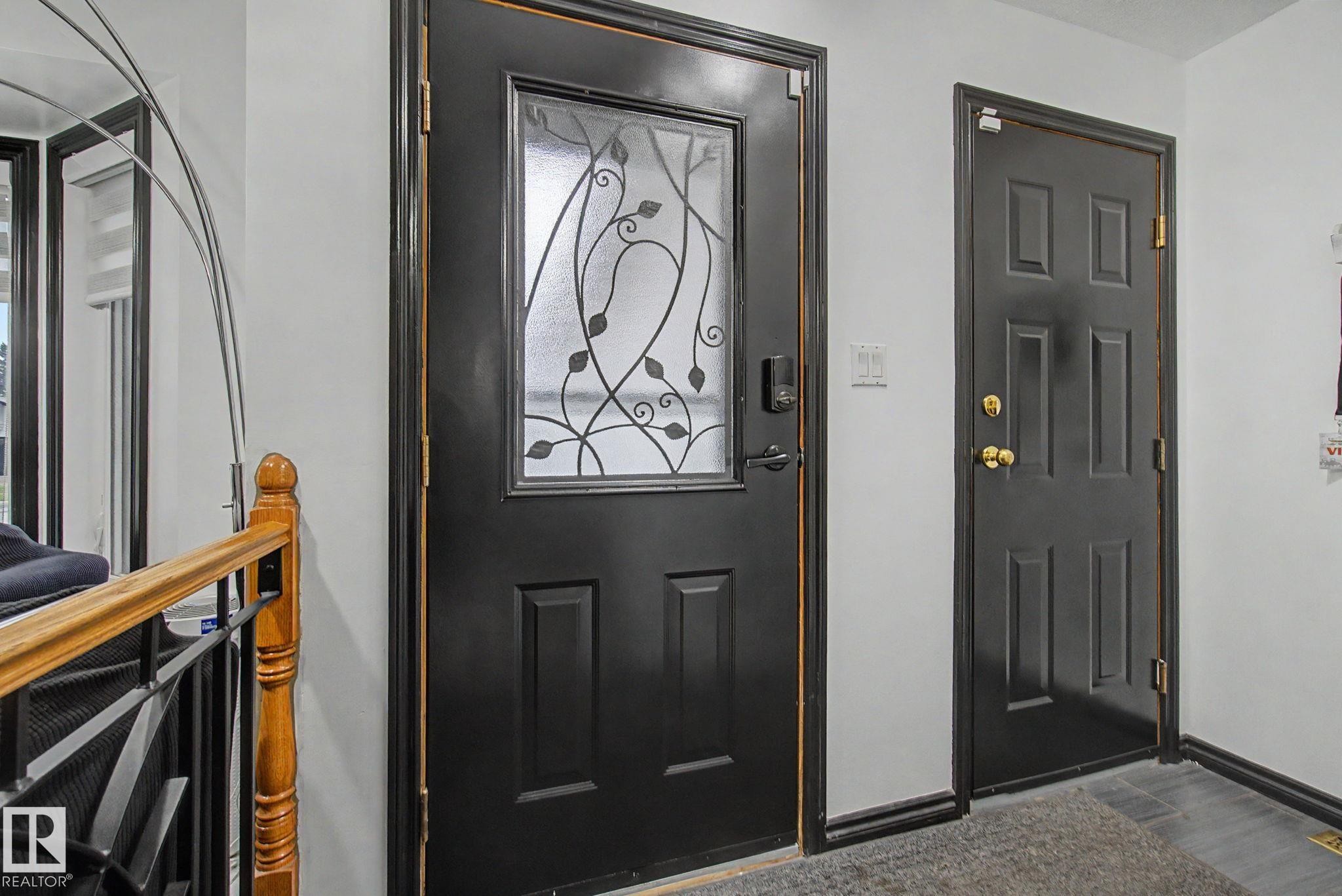 Black paneled entry door with decorative glass inlay and modern hardware - 242 Northmount Drive, Wetaskiwin, AB