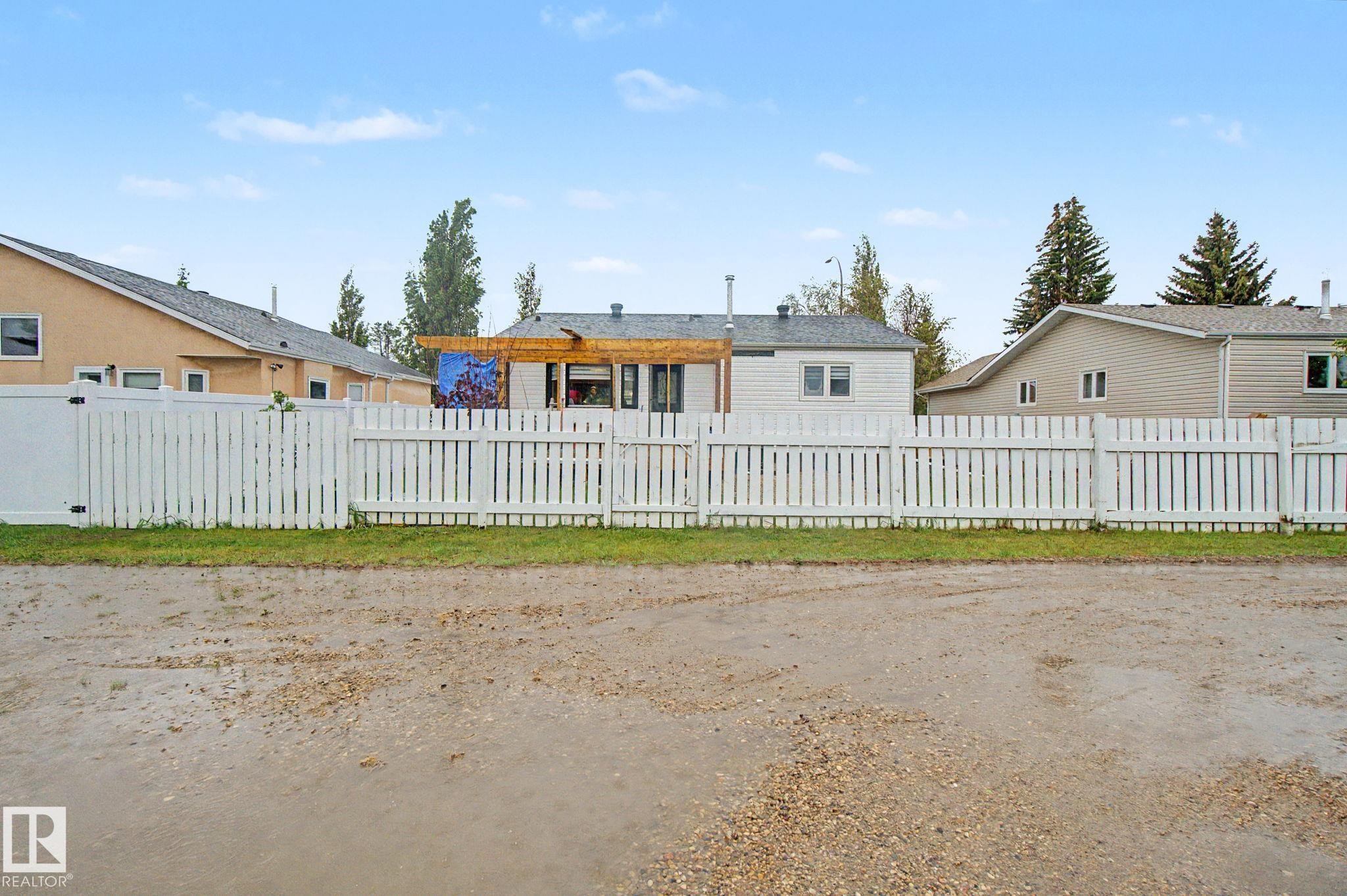 White picket fence enclosing a backyard with a wooden pergola - 242 Northmount Drive, Wetaskiwin, AB