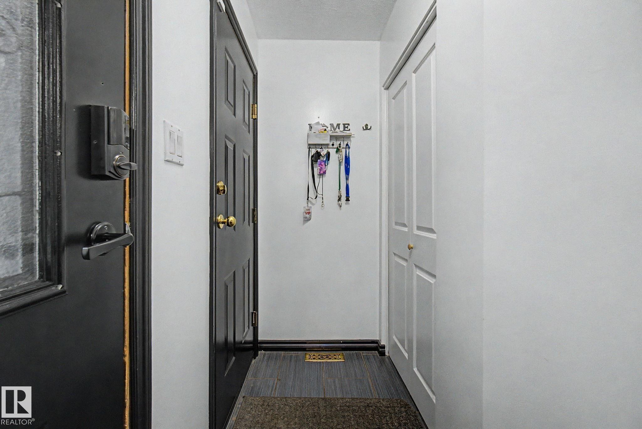 Entryway featuring a dark paneled door, light wood-finish flooring, and a bi-fold closet - 242 Northmount Drive, Wetaskiwin, AB