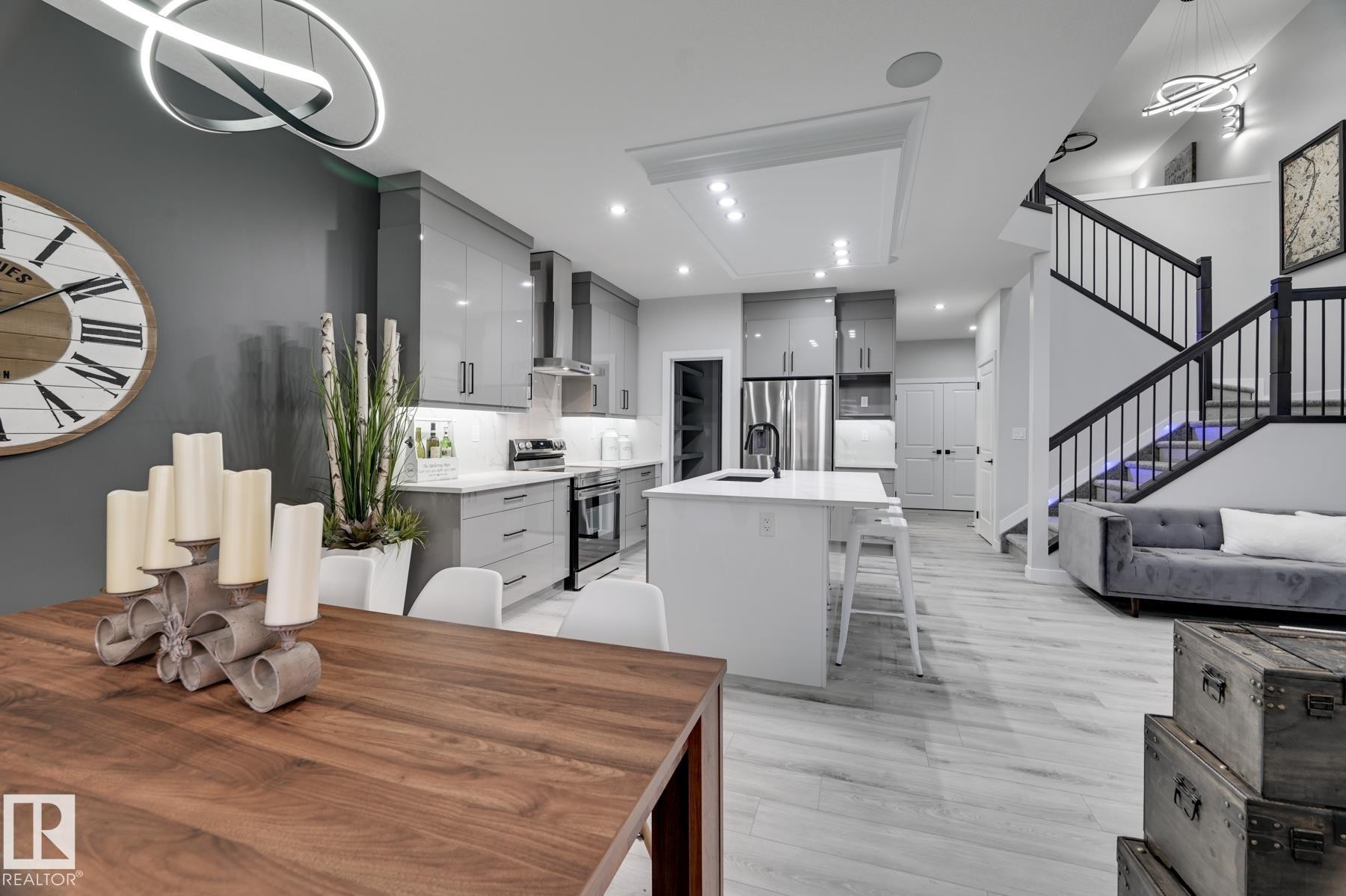 Open-concept living area featuring a modern kitchen with high-gloss cabinetry, a central island with integrated seating, and stainless steel appliances - 54 Chartres Close, St. Albert, AB - Indoor