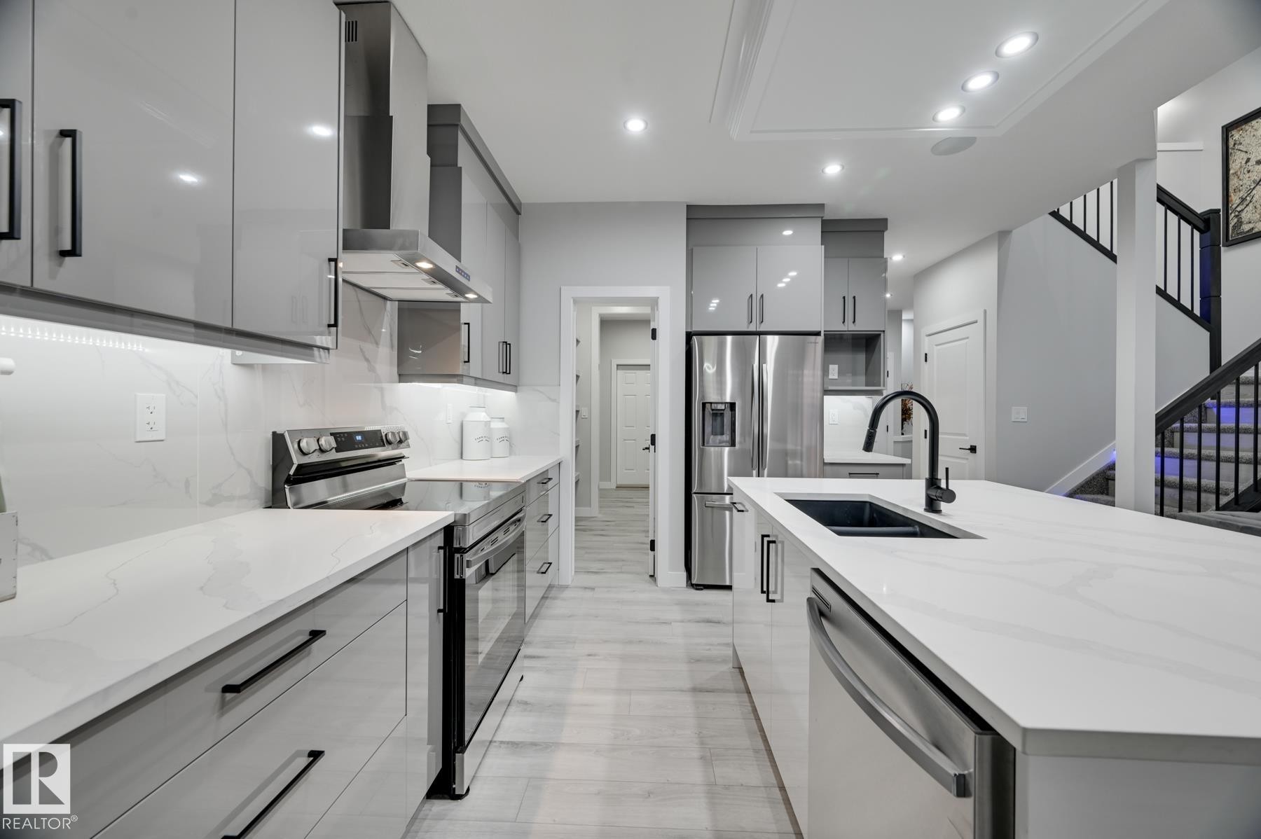 Modern kitchen featuring gray high-gloss cabinetry, stainless steel appliances, white countertops with subtle veining, and an undermount sink with a matte black faucet - 54 Chartres Close, St. Albert, AB - Indoor Photo Showing Kitchen With Double Sink With Upgraded Kitchen