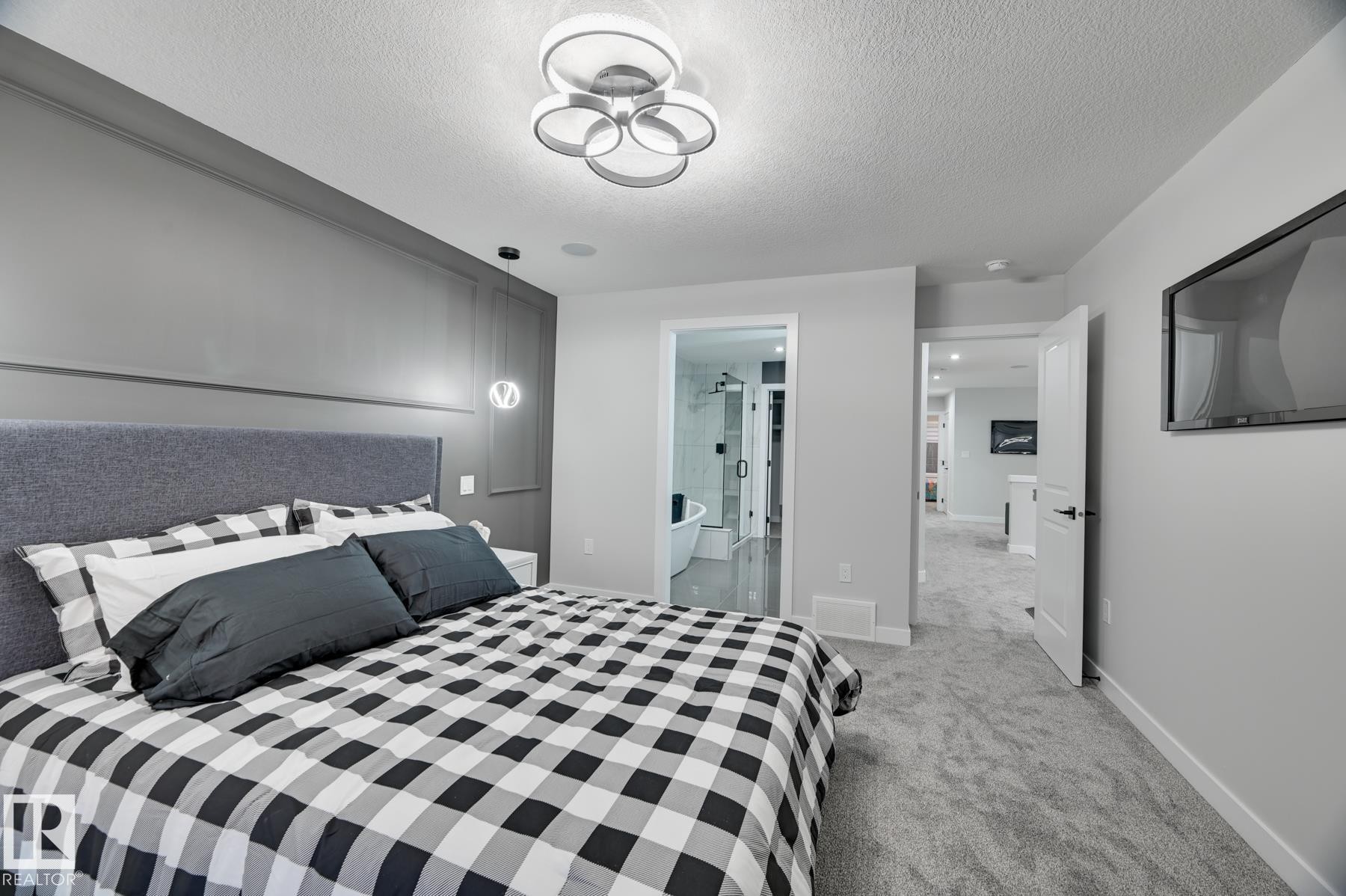 Spacious bedroom with grey textured carpet, a contemporary ceiling light fixture, and a built-in wall panel accent behind the bed - 54 Chartres Close, St. Albert, AB - Indoor Photo Showing Bedroom