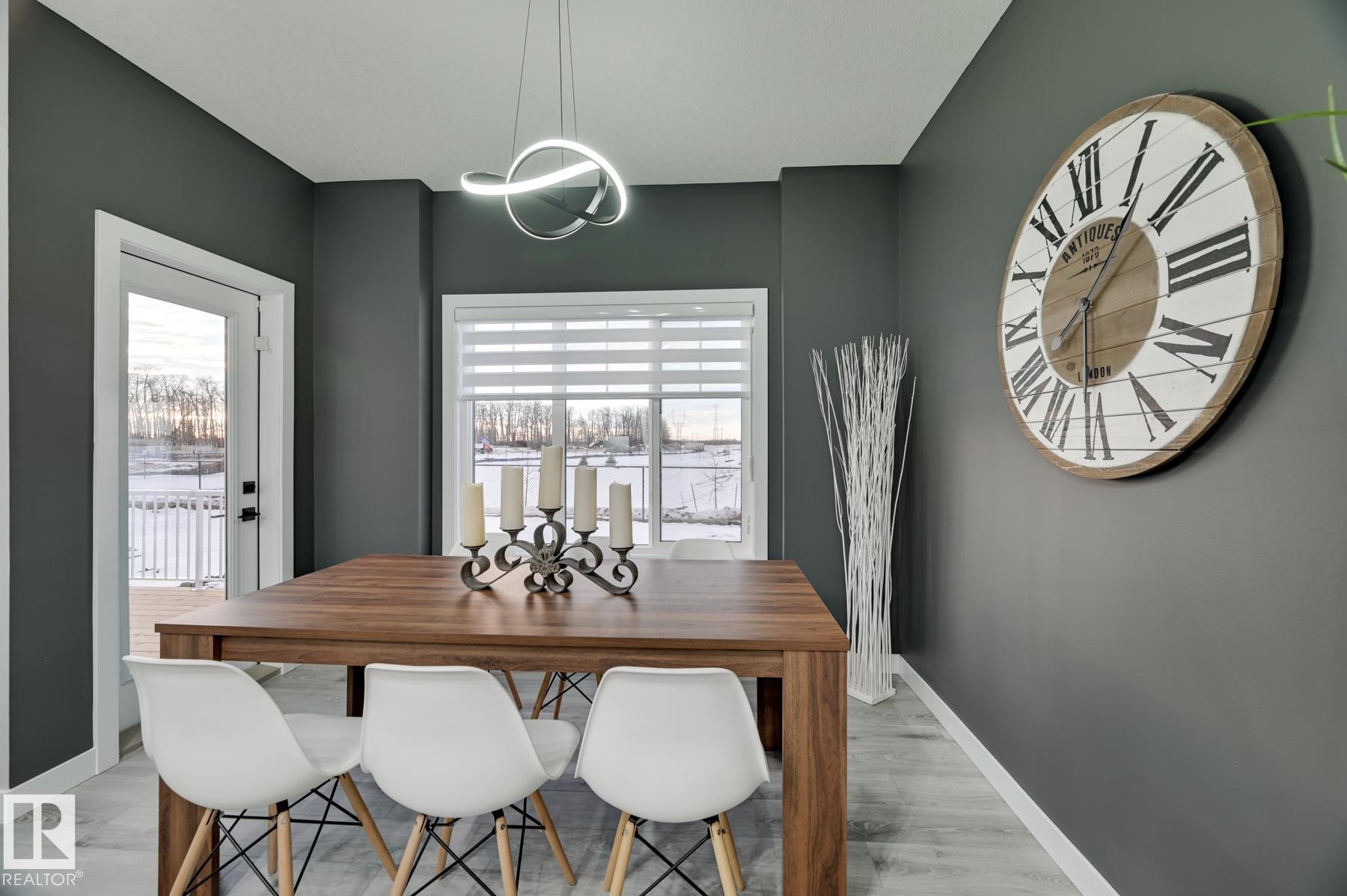 Dining area featuring light wood-finish flooring, dark gray walls, and a contemporary pendant light fixture - 54 Chartres Close, St. Albert, AB - Indoor Photo Showing Dining Room