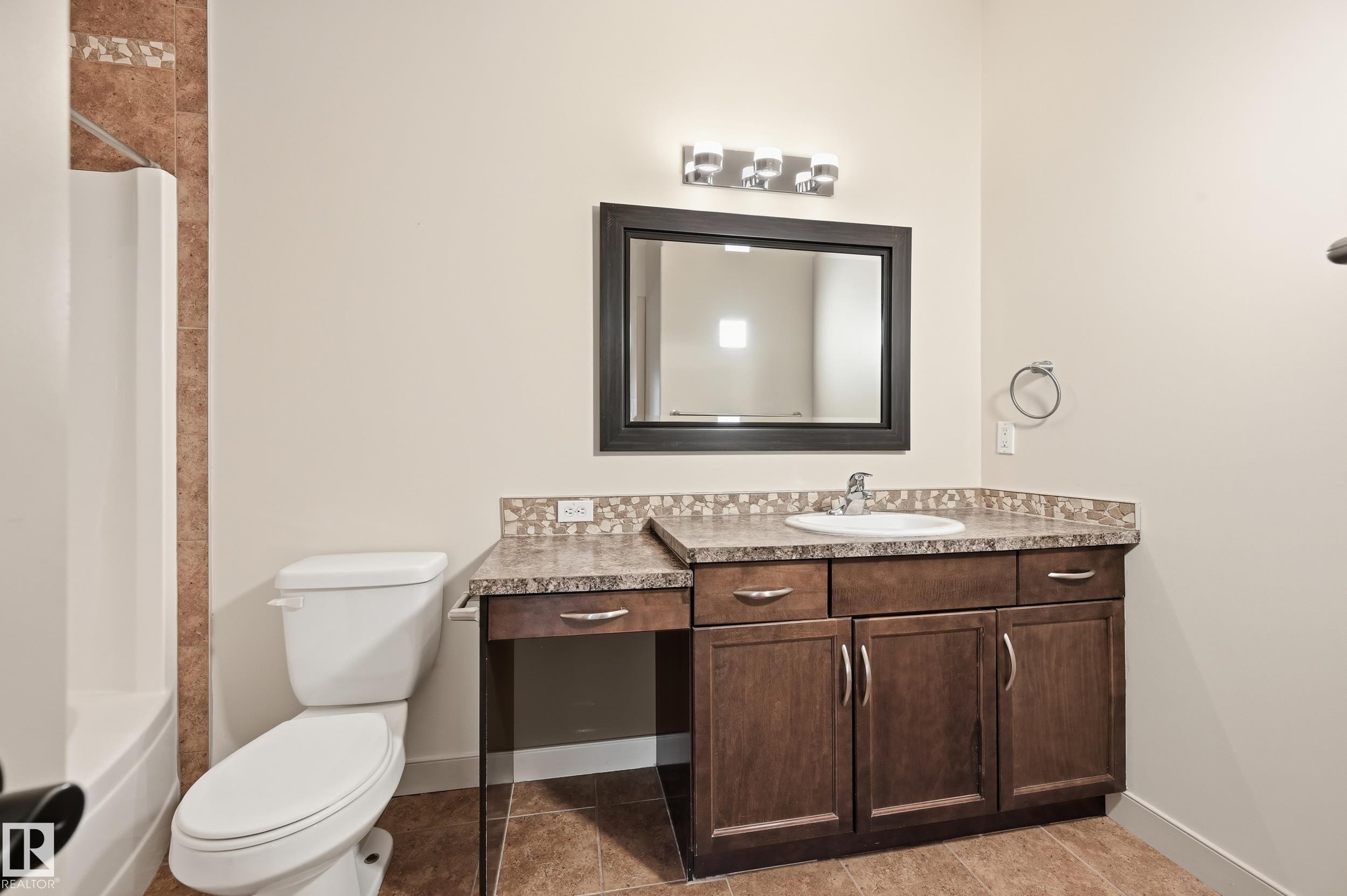 Vanity with integrated sink, dark wood-finish cabinetry, and stone-look countertop - 50 2565 Hanna Crescent, Edmonton, AB