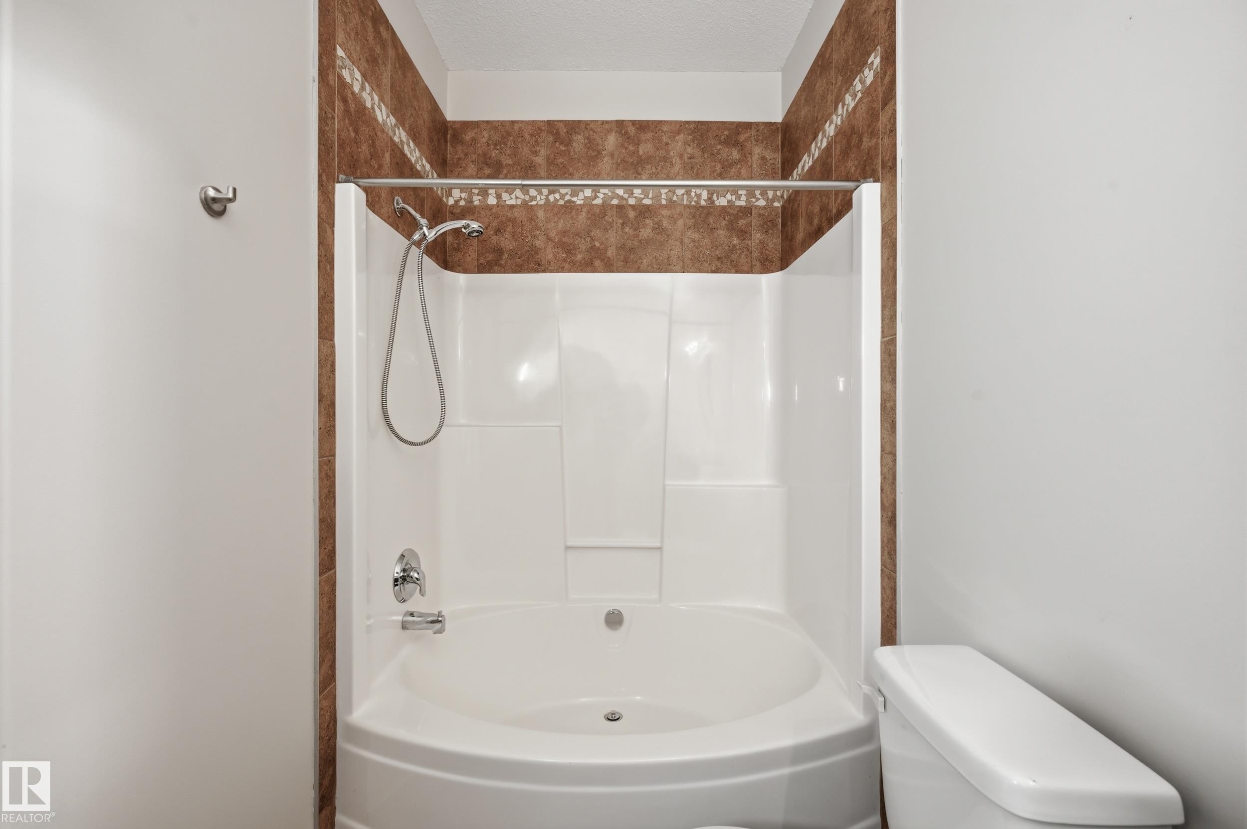 Bathtub and shower combination featuring a white surround and a curved basin - 50 2565 Hanna Crescent, Edmonton, AB
