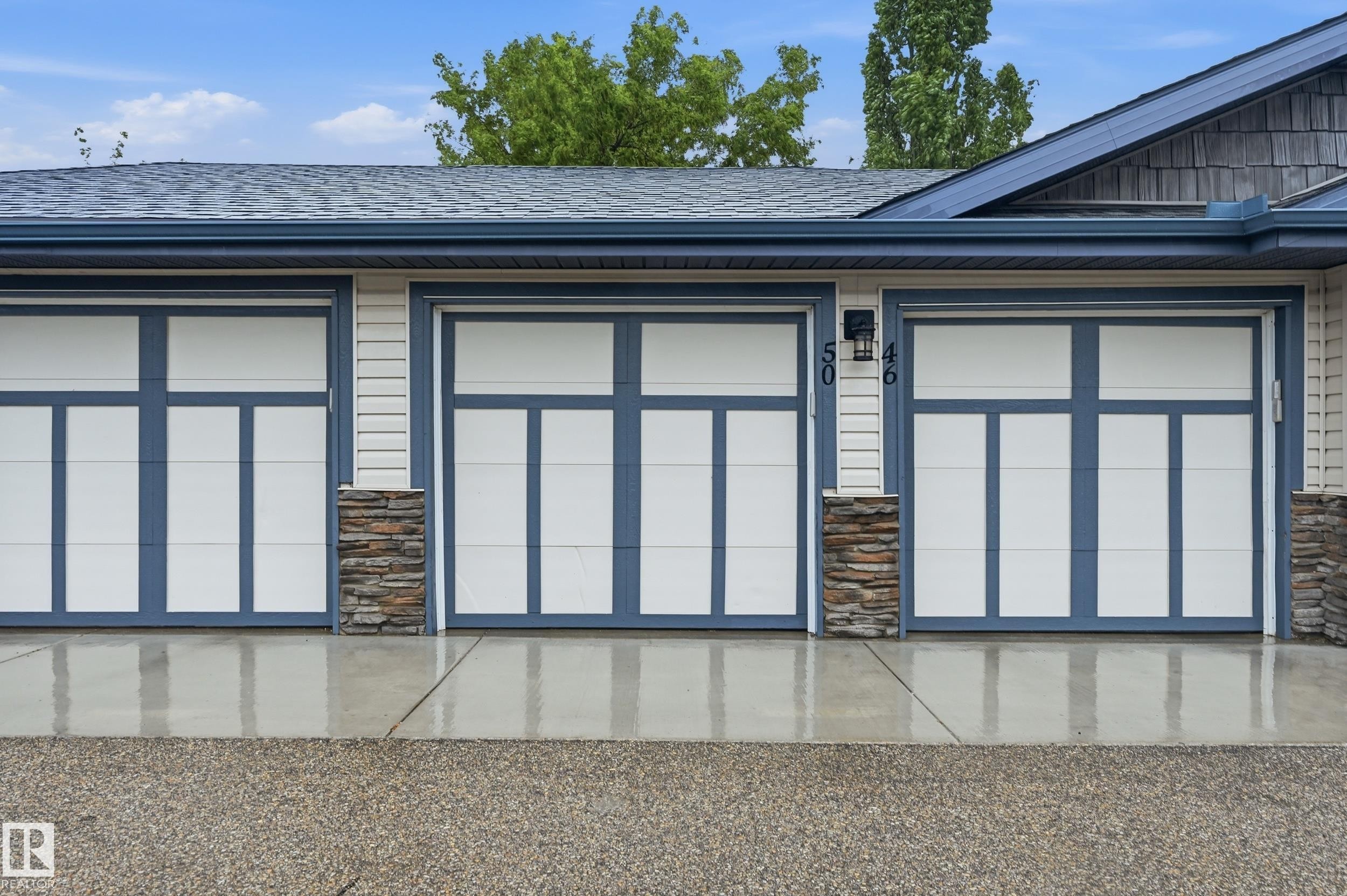Triple-bay garage featuring contemporary doors with frosted glass panels and blue trim - 50 2565 Hanna Crescent, Edmonton, AB
