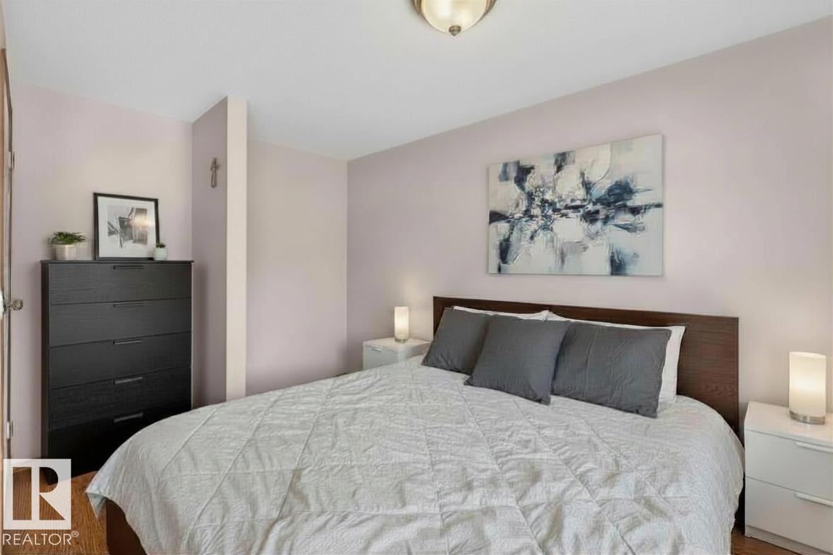 Bedroom featuring wood-finish flooring, a wood-paneled headboard, and soft wall color - 14648 54 Street, Edmonton, AB
