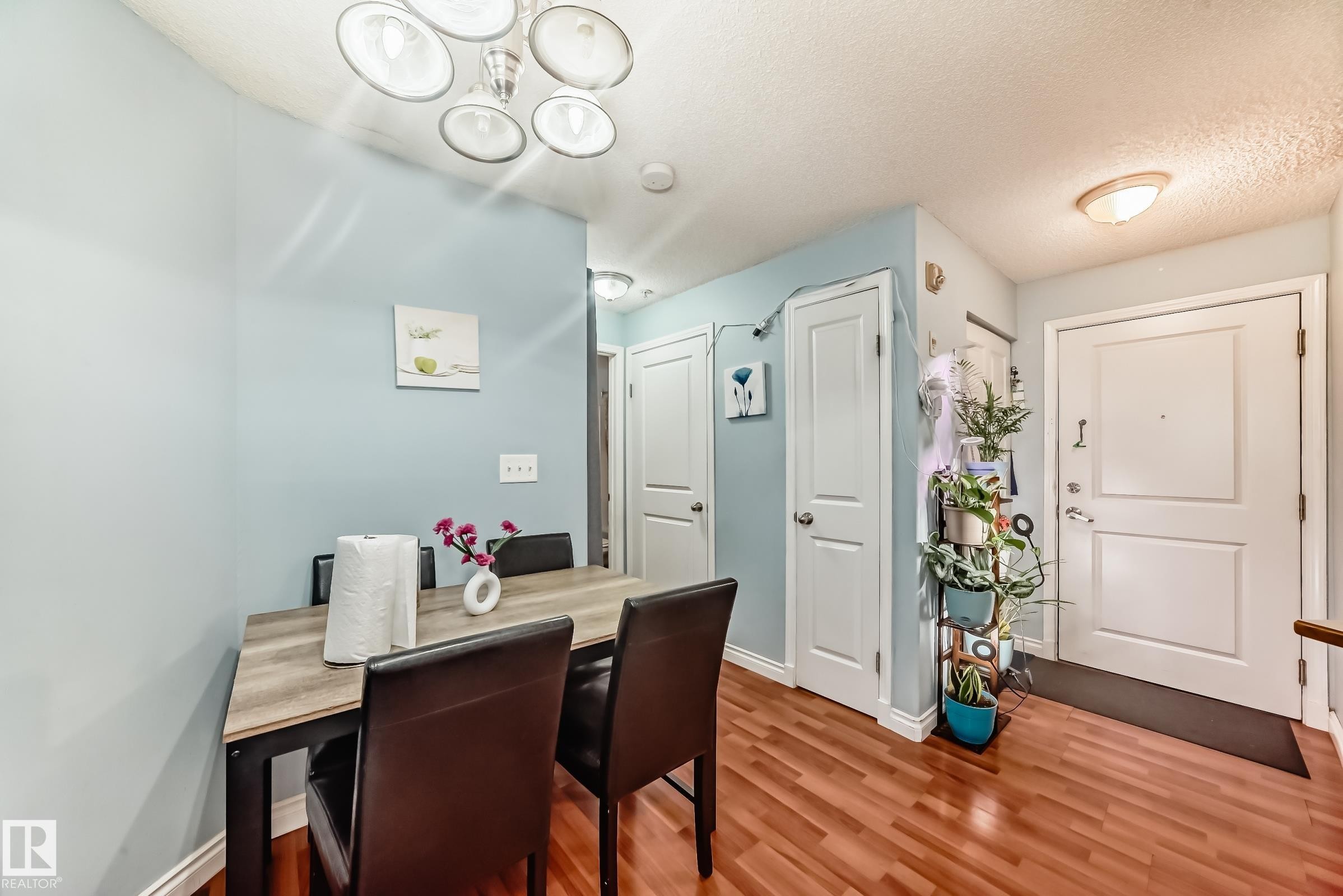 Hardwood-finish flooring in an interior space featuring light blue wall paint and white trim - 108 10535 122 Street, Edmonton, AB