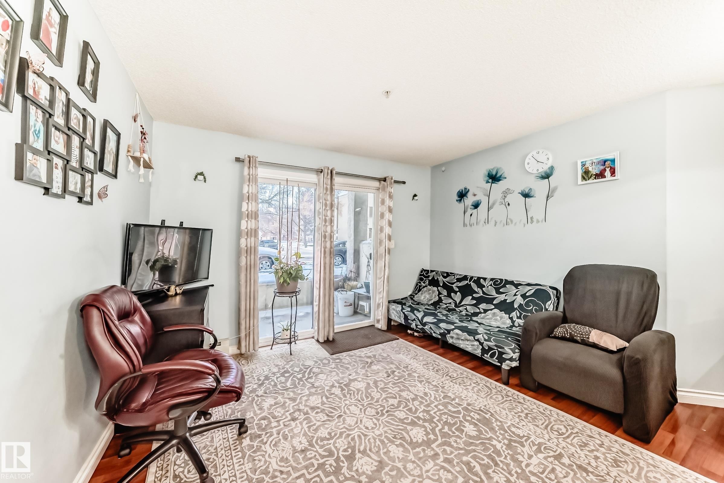 Living area featuring wood-finish flooring, light-colored walls, and a sliding glass door providing exterior access - 108 10535 122 Street, Edmonton, AB