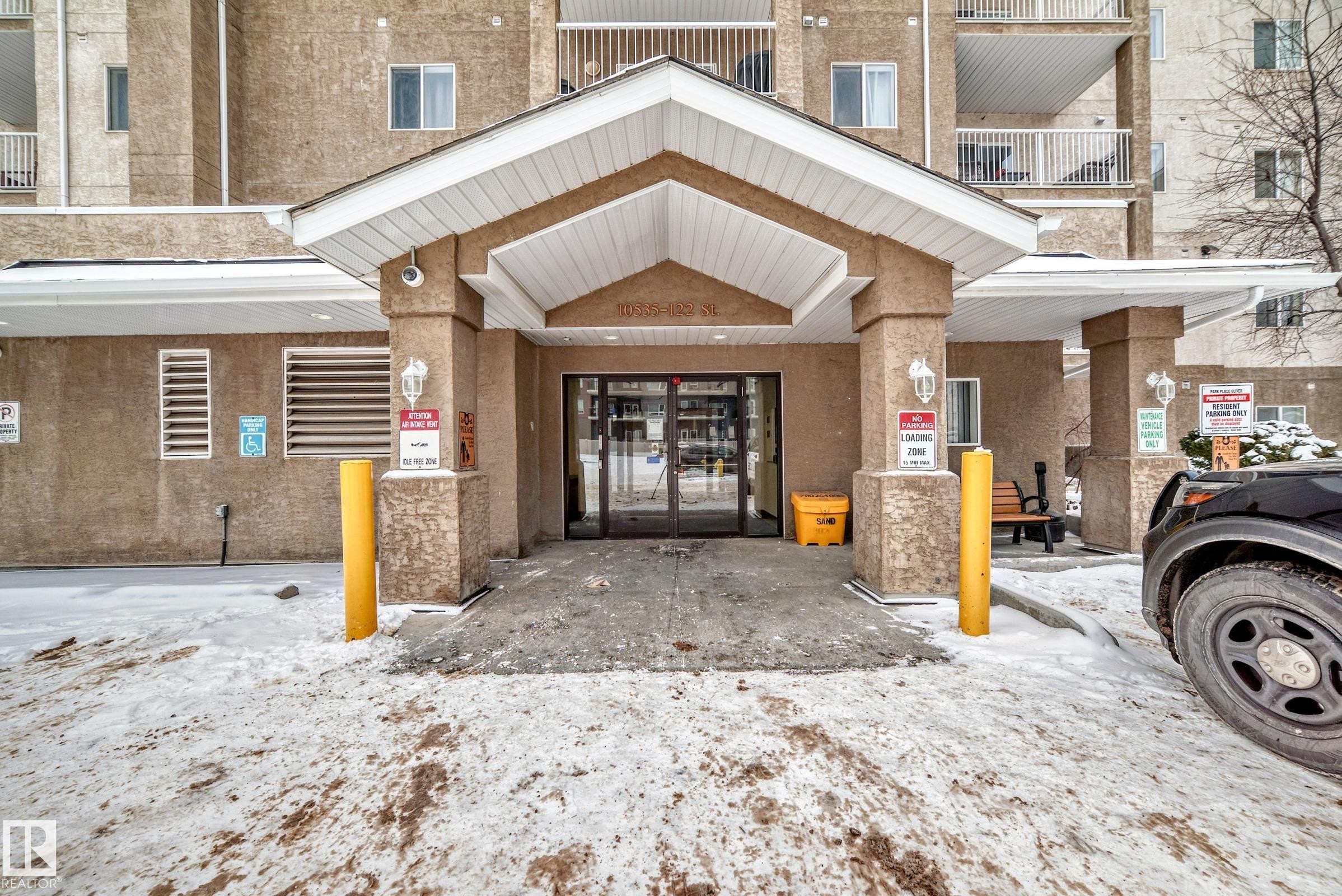 Building entrance featuring a covered portico with decorative pillars and overhead lighting - 108 10535 122 Street, Edmonton, AB