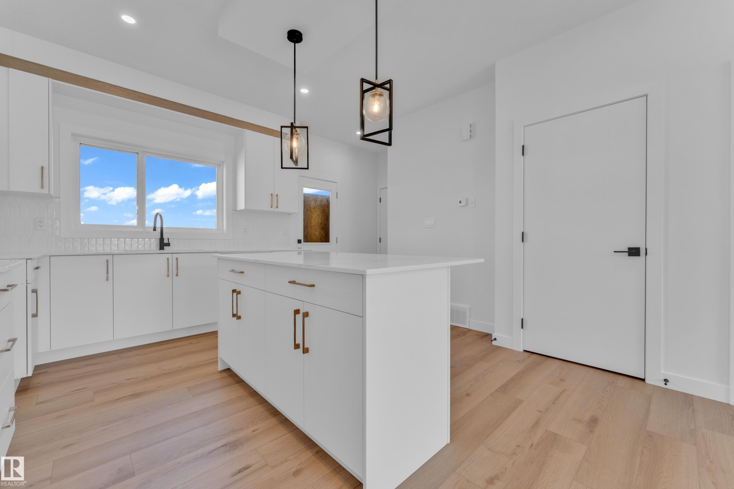 Modern kitchen featuring a central island with a white countertop and brass-finish hardware - 175 Graybriar Drive, Stony Plain, AB