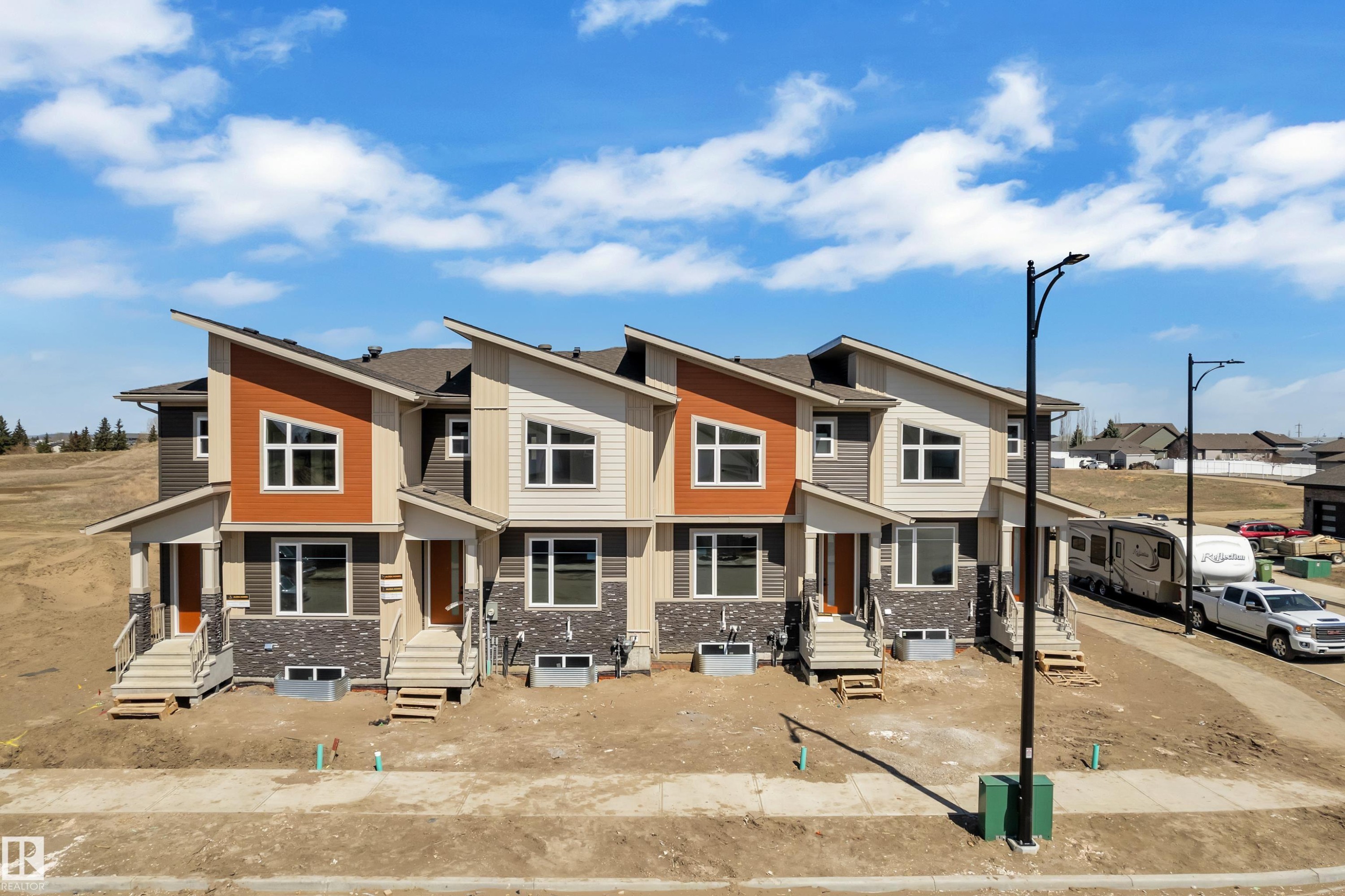 Modern townhome exteriors featuring varied siding textures, stone veneer accents, and contemporary rooflines - 175 Graybriar Drive, Stony Plain, AB