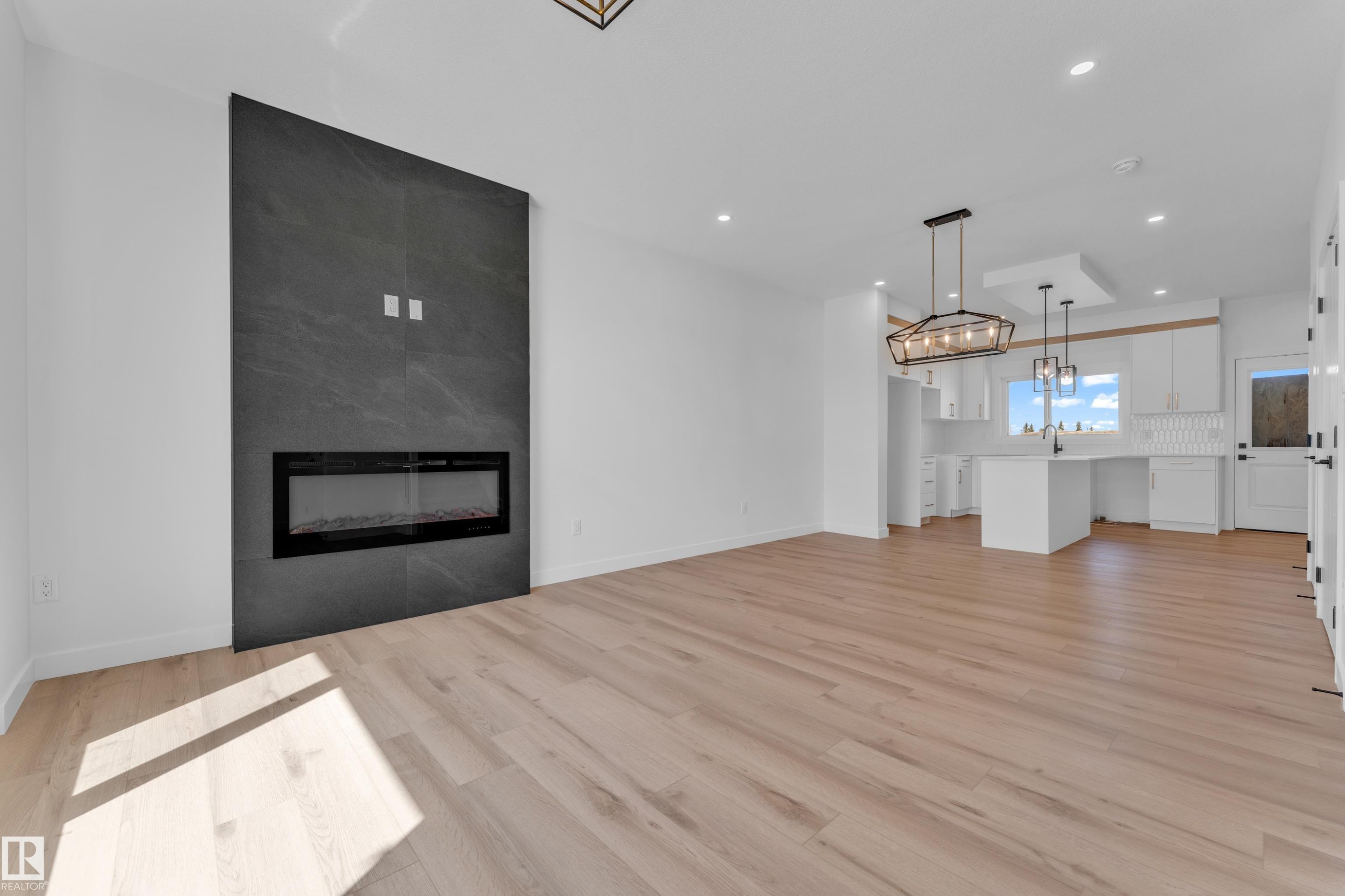 Open-concept living space with a floor-to-ceiling dark tile fireplace surround featuring an electric insert - 175 Graybriar Drive, Stony Plain, AB