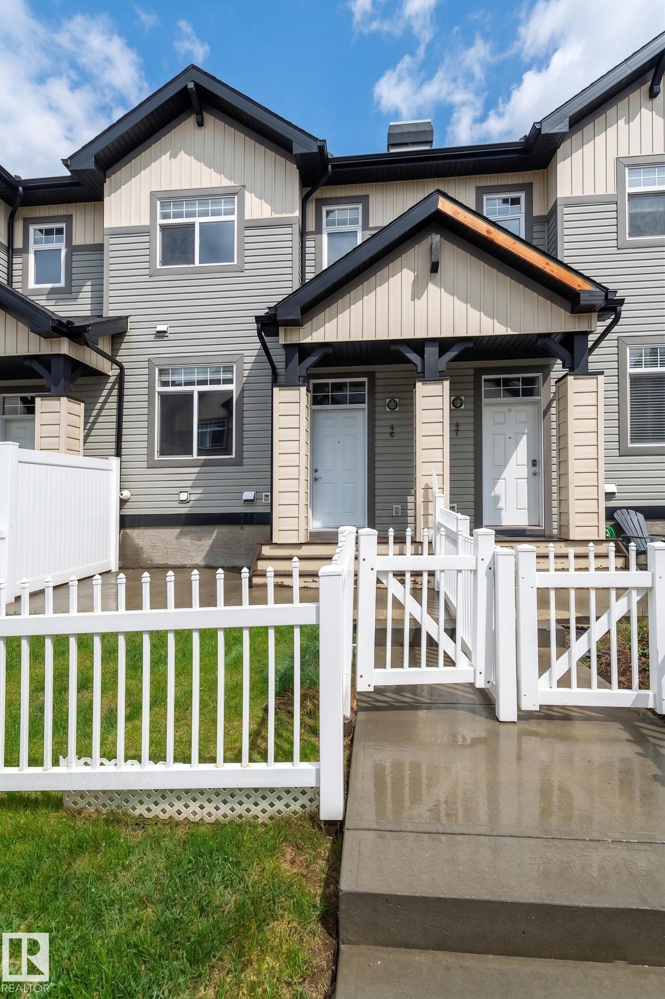 Contemporary townhome exterior featuring light gray siding with cream-colored gables, white window frames, and contrasting dark trim - 46 465 Hemingway Road, Edmonton, AB
