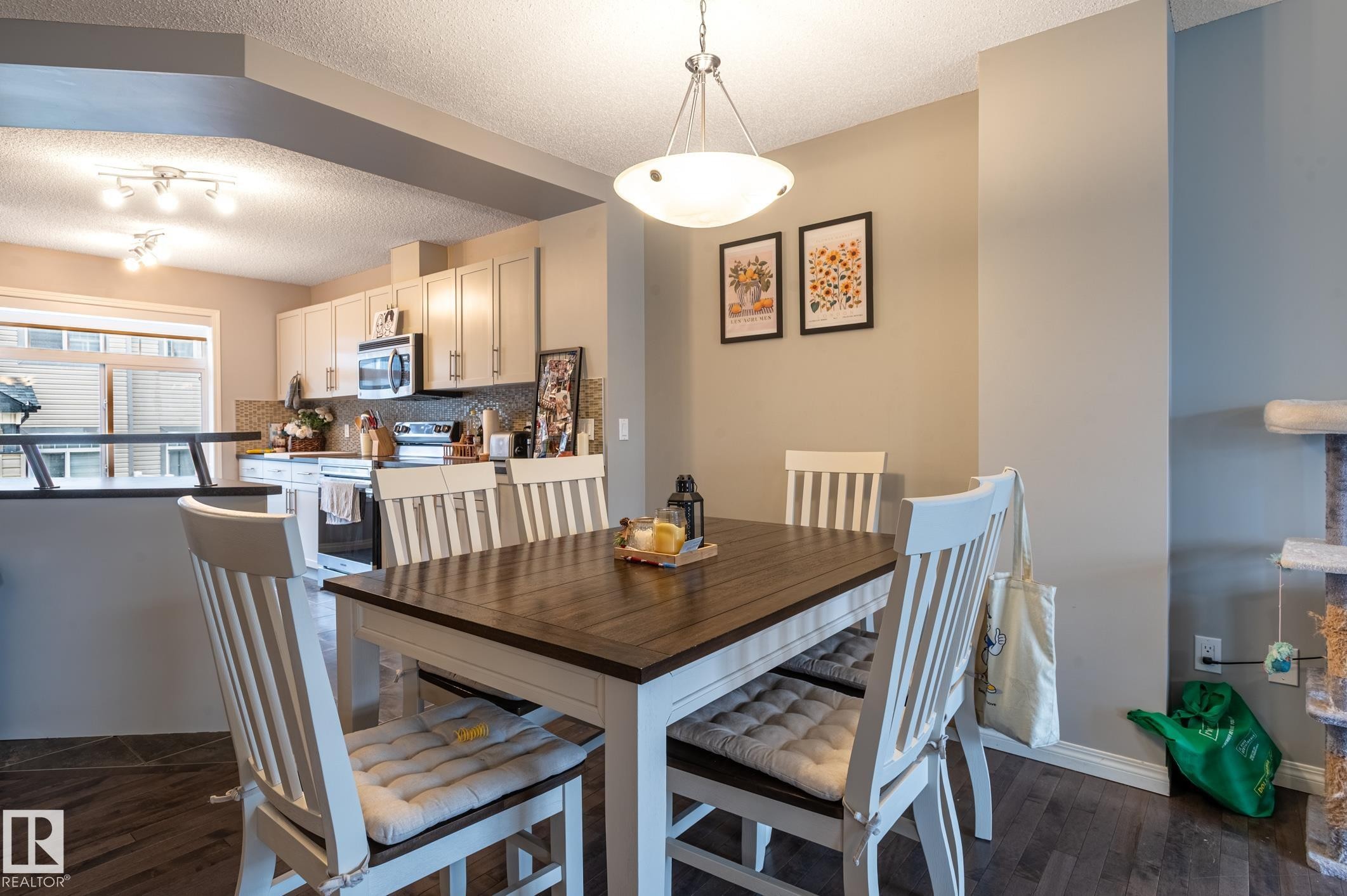 Open-concept dining area with wood-finish flooring, featuring a contemporary pendant light fixture - 46 465 Hemingway Road, Edmonton, AB