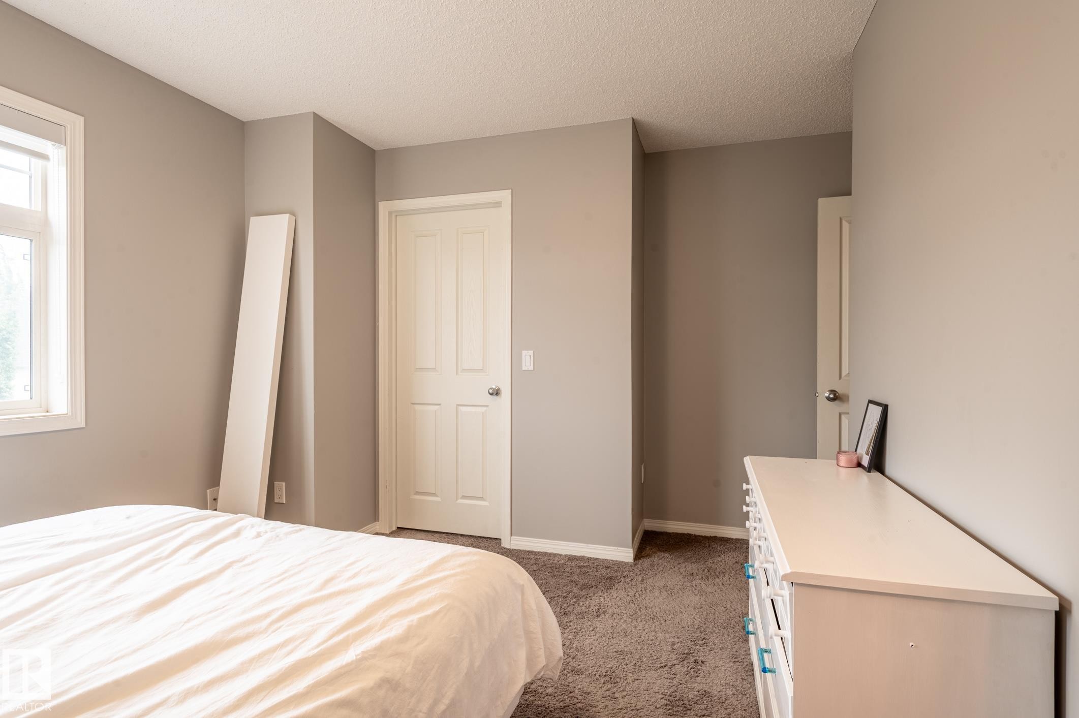 Bedroom with neutral-toned walls, a four-panel interior door, and a textured carpeted floor - 46 465 Hemingway Road, Edmonton, AB