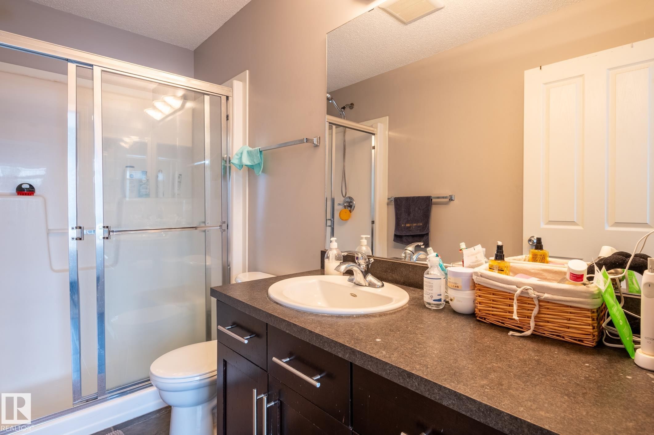 Bathroom featuring a dark wood-finish vanity with a white oval sink, dark countertop, and silver-tone fixtures - 46 465 Hemingway Road, Edmonton, AB