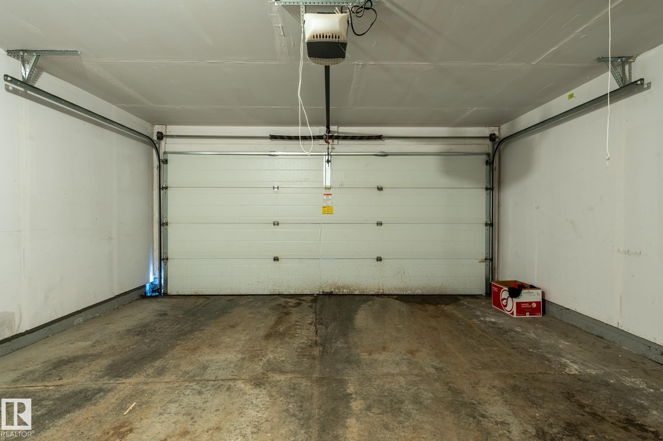 Attached garage with a white sectional door and automatic opener - 46 465 Hemingway Road, Edmonton, AB