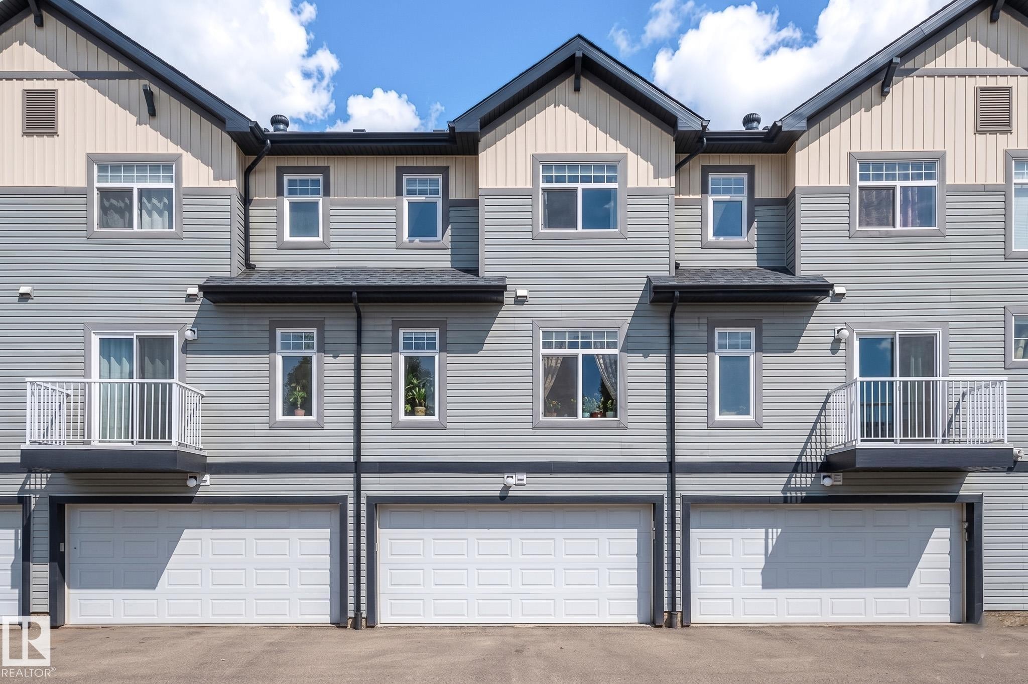 Multi-level townhome exterior featuring light gray horizontal siding and contrasting beige vertical siding - 46 465 Hemingway Road, Edmonton, AB