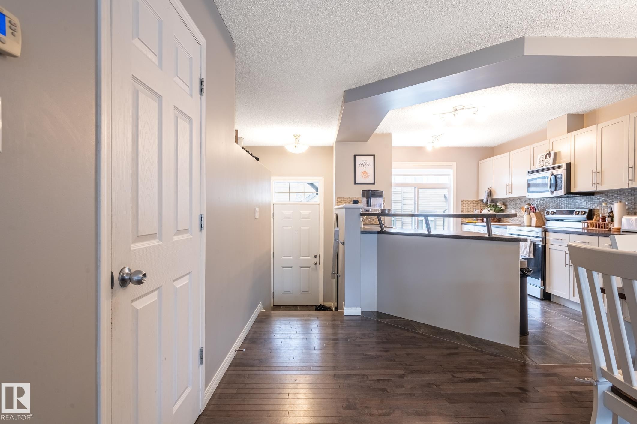 Entryway featuring dark wood-finish flooring, a white six-panel door, and a thermostat - 46 465 Hemingway Road, Edmonton, AB
