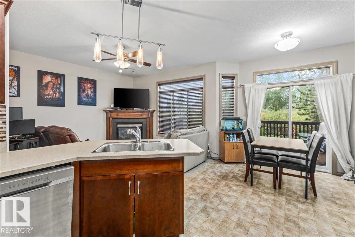Open-concept living area featuring a kitchen island with sink, stainless steel dishwasher, wood-finish cabinetry, and light-toned countertops - 229 41 Summerwood Boulevard, Sherwood Park, AB - Indoor