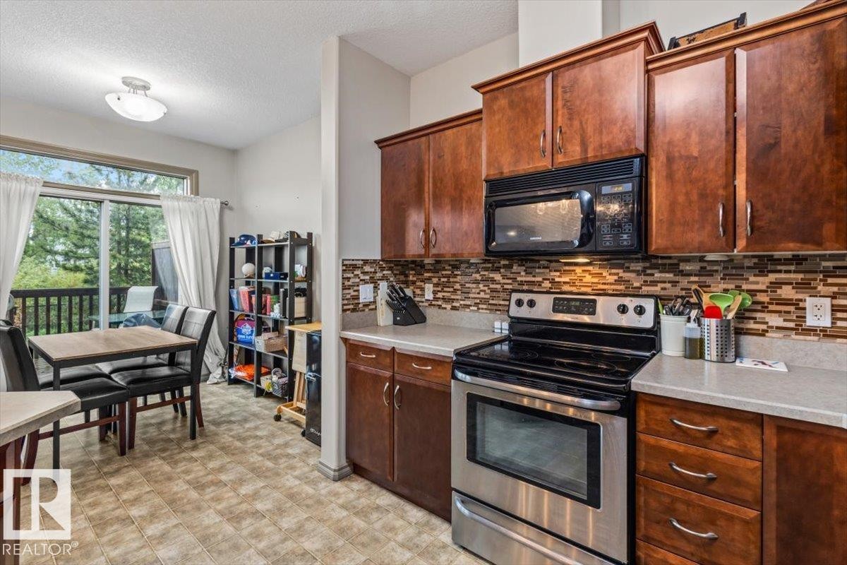 Kitchen featuring wood cabinetry, stainless steel range, and a mosaic tile backsplash - 229 41 Summerwood Boulevard, Sherwood Park, AB - Indoor Photo Showing Kitchen