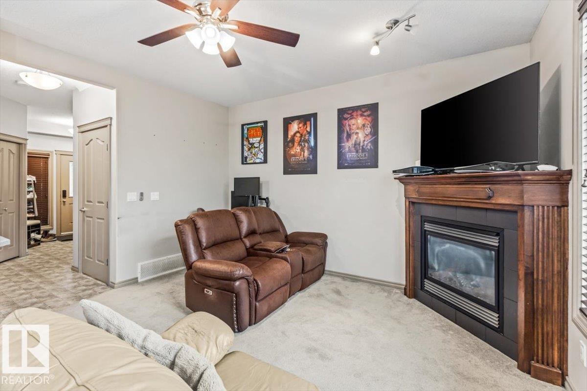 Living area featuring a wood-finish fireplace mantel and a ceiling fan with integrated lighting - 229 41 Summerwood Boulevard, Sherwood Park, AB - Indoor Photo Showing Living Room With Fireplace
