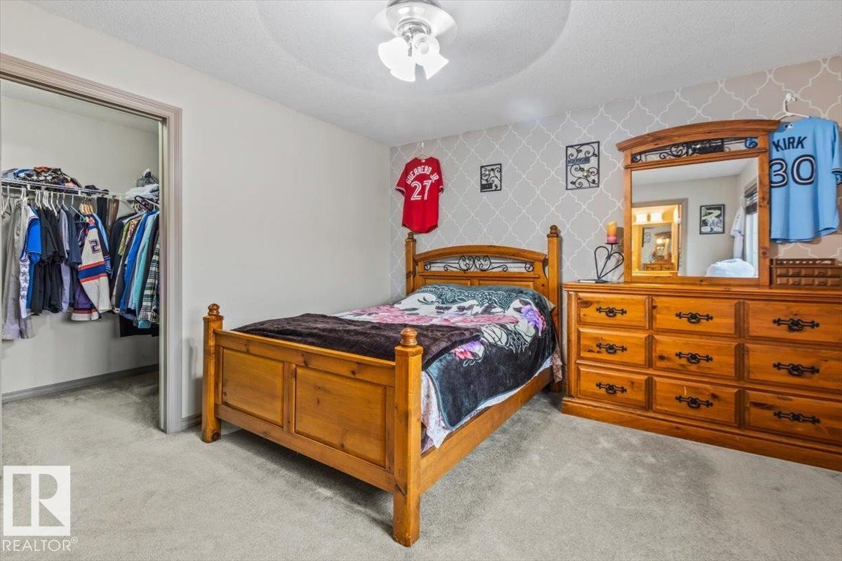 Carpeted room featuring a ceiling fan, a closet with bifold doors, and a decorative accent wall - 229 41 Summerwood Boulevard, Sherwood Park, AB - Indoor Photo Showing Bedroom