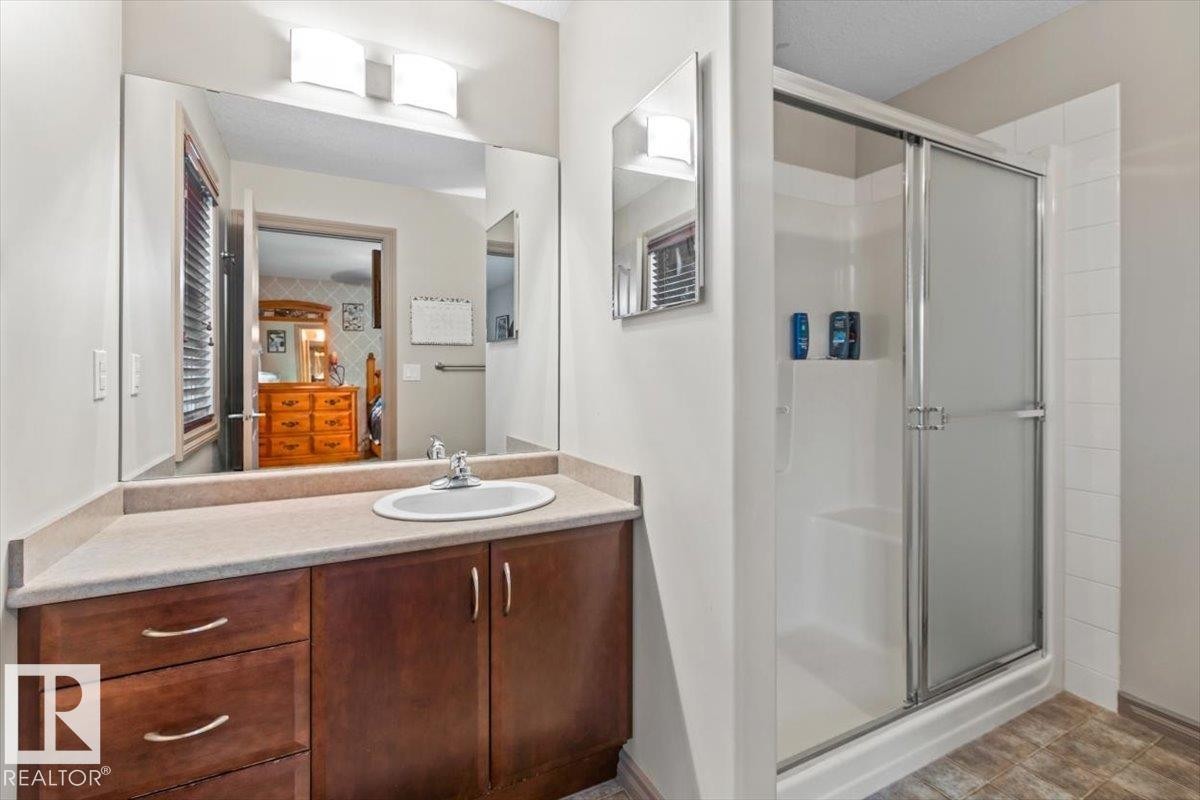 Bathroom featuring a vanity with a light-toned countertop, an integrated sink, and dark wood cabinetry - 229 41 Summerwood Boulevard, Sherwood Park, AB - Indoor Photo Showing Bathroom