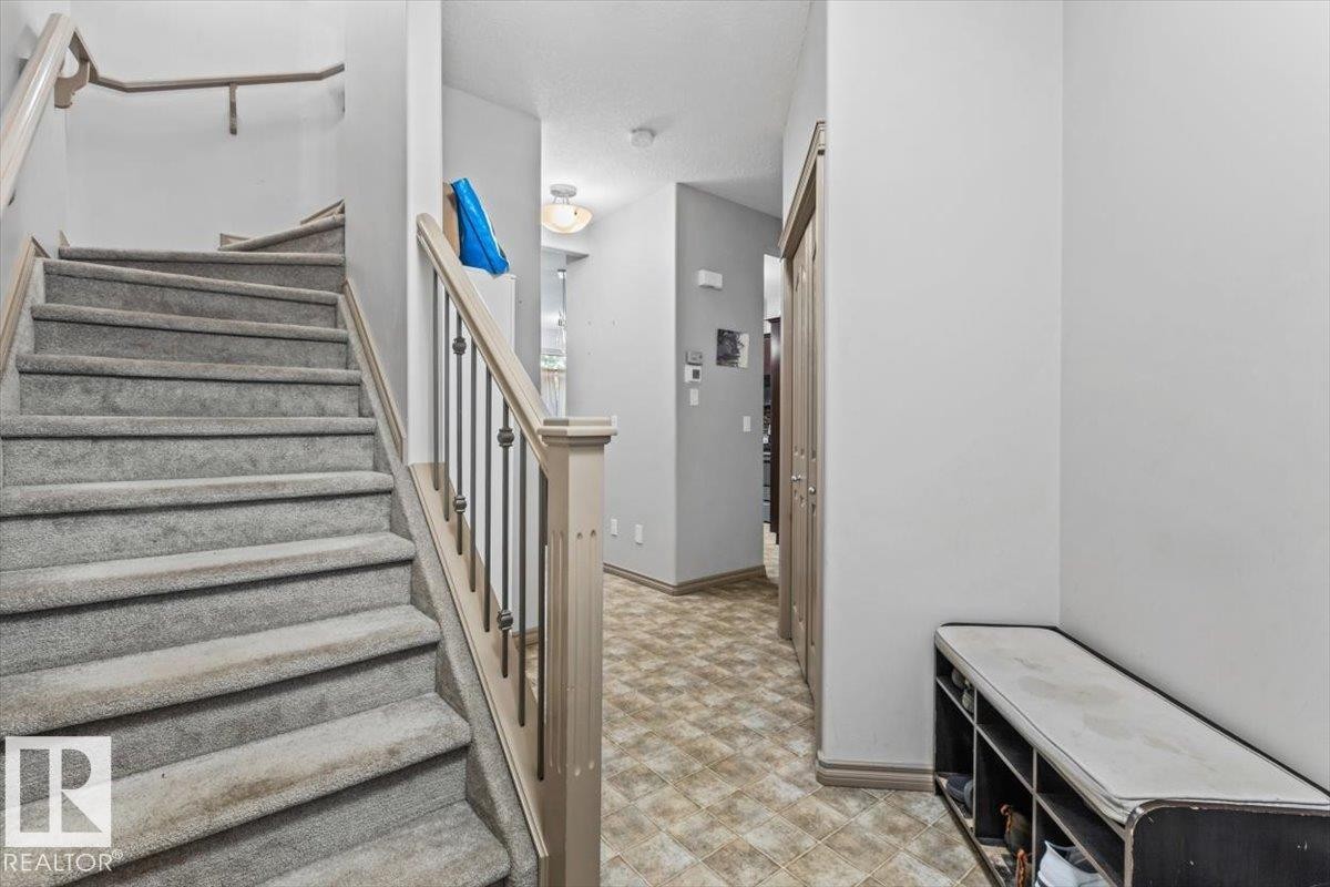 Carpeted staircase with light-toned wood newel post and balusters featuring metal spindles - 229 41 Summerwood Boulevard, Sherwood Park, AB - Indoor Photo Showing Other Room
