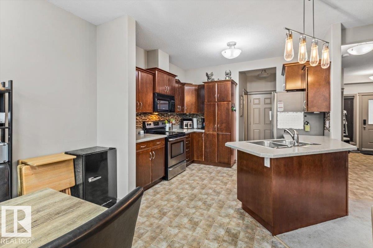 Kitchen featuring wood-finish cabinetry, stainless steel appliances, and a tiled backsplash - 229 41 Summerwood Boulevard, Sherwood Park, AB - Indoor Photo Showing Kitchen With Double Sink