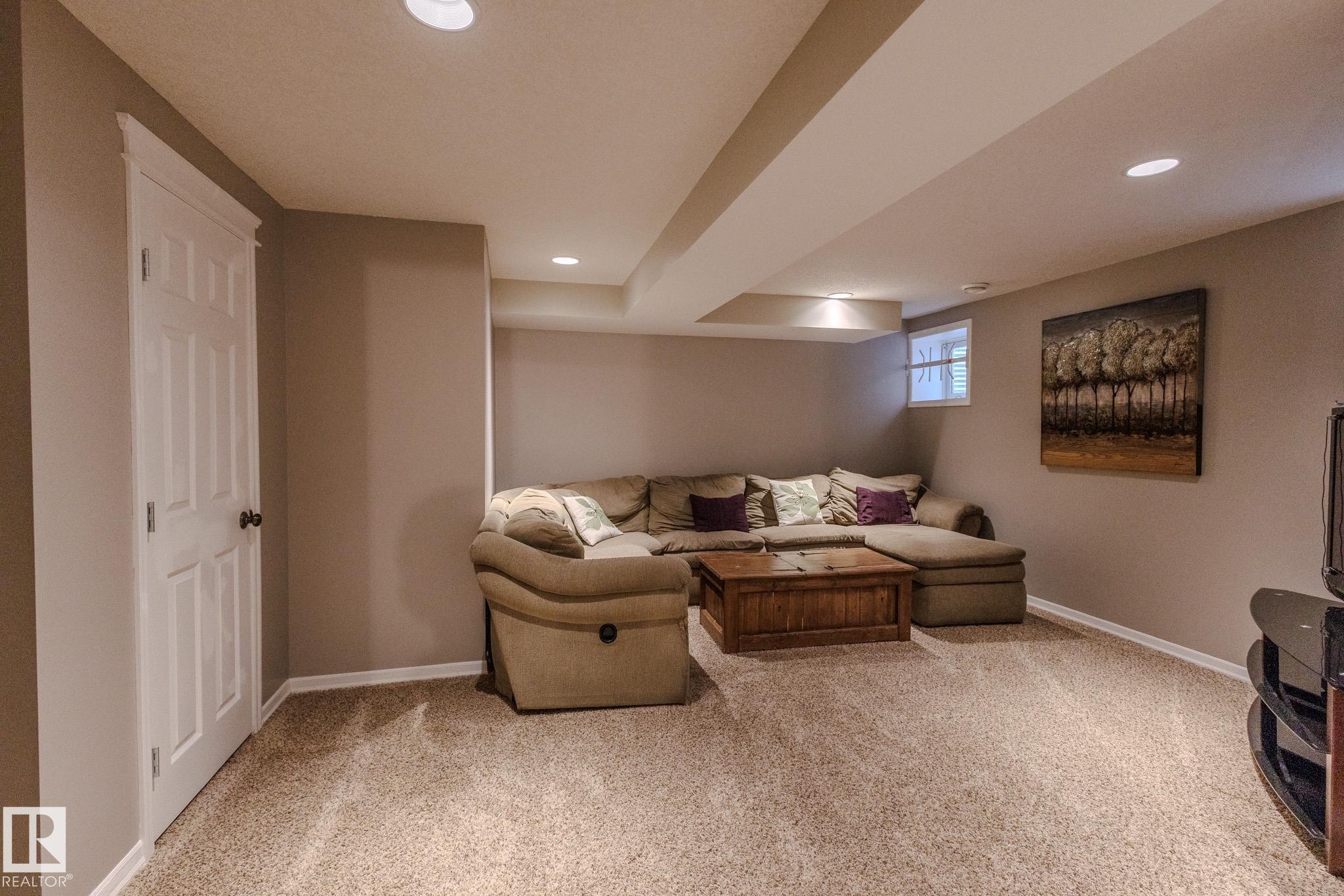 Finished lower level featuring recessed lighting, a neutral color palette, carpet flooring, a white paneled door with dark hardware, and a small window - 7207 14A Avenue, Edmonton, AB - Indoor