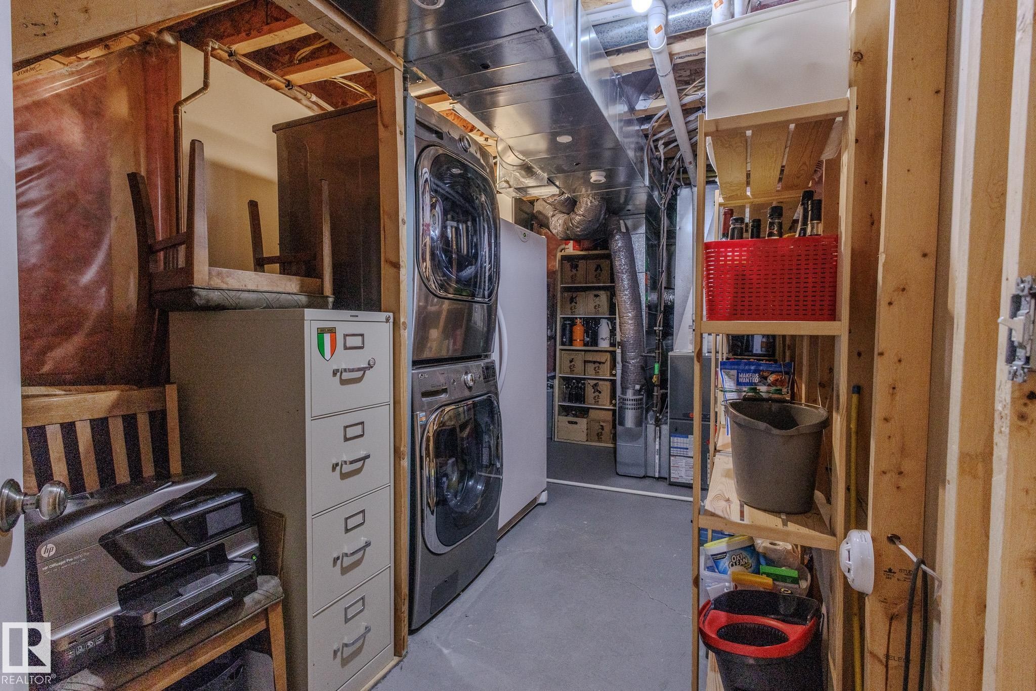 Laundry area featuring a stacked washer and dryer, exposed ceiling joists, and visible ductwork - 7207 14A Avenue, Edmonton, AB - Indoor Photo Showing Laundry Room