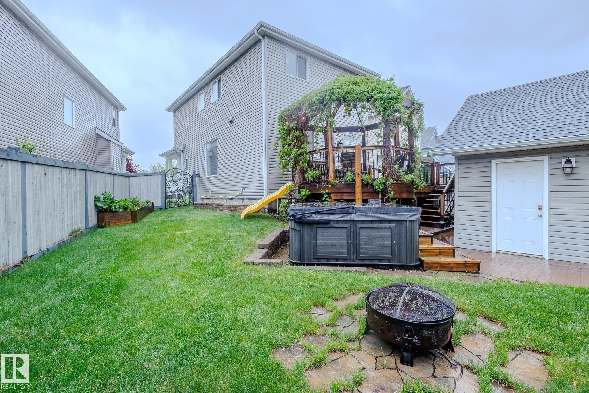 Expansive backyard featuring a large wooden deck with a pergola, a built-in hot tub, and a separate utility shed - 7207 14A Avenue, Edmonton, AB - Outdoor