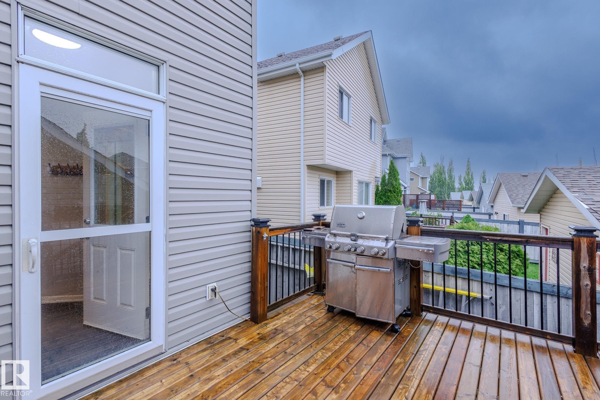 Spacious wood-finish deck with dark wood-finish railings and black metal balusters - 7207 14A Avenue, Edmonton, AB - Outdoor With Exterior